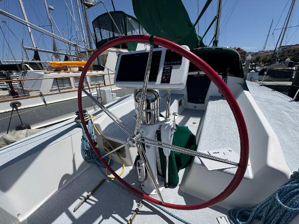 Sailboat cockpit of a 2000 Wyliecat 48 with red steering wheel and navigation equipment.
