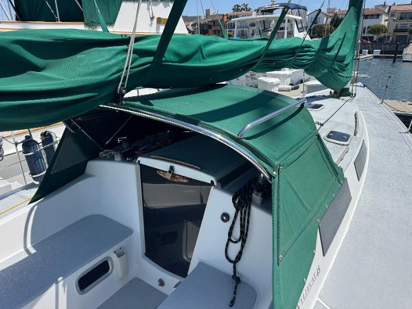 Sailboat with green canopy, Wyliecat 48, 2000 model, docked at marina.