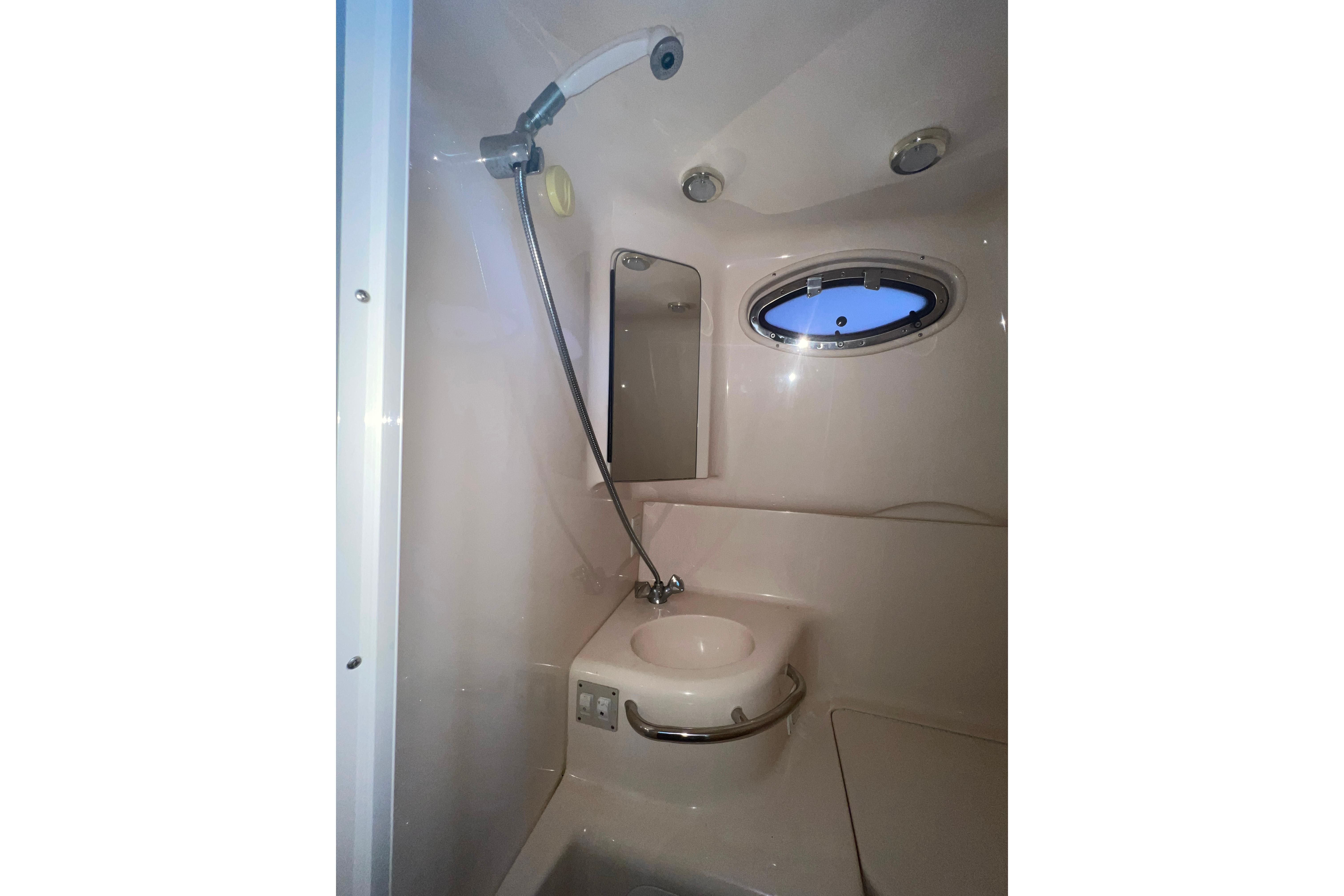 1999 Sea Ray 290 Sundancer bathroom with shower, sink, and porthole window.