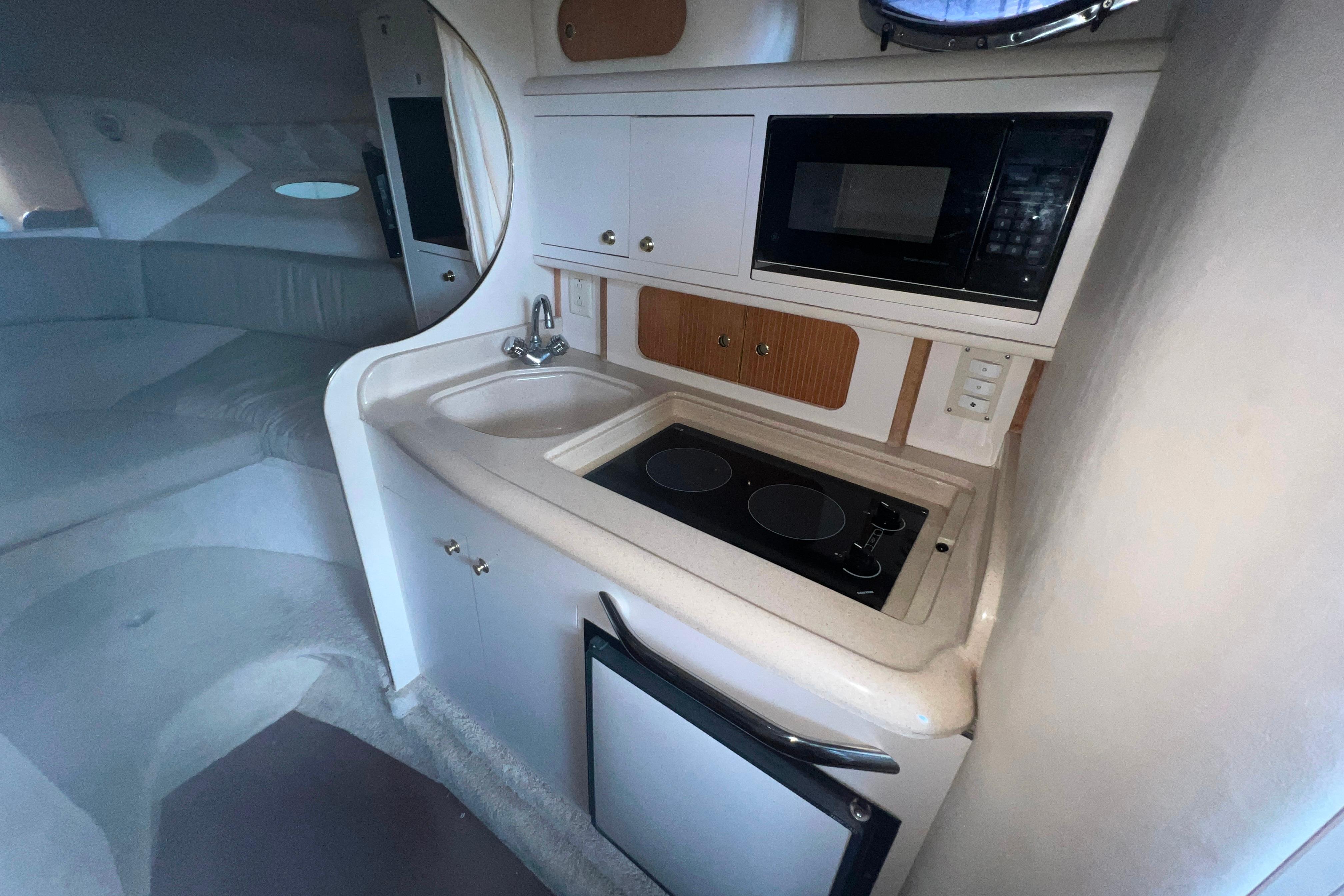 1999 Sea Ray 290 Sundancer interior with kitchenette, sink, stove, and microwave.