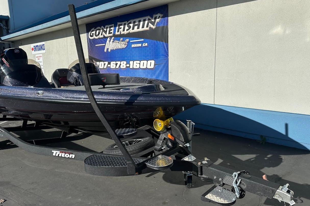 2026 Triton 18 TrX boat on trailer, parked outside a fishing store.