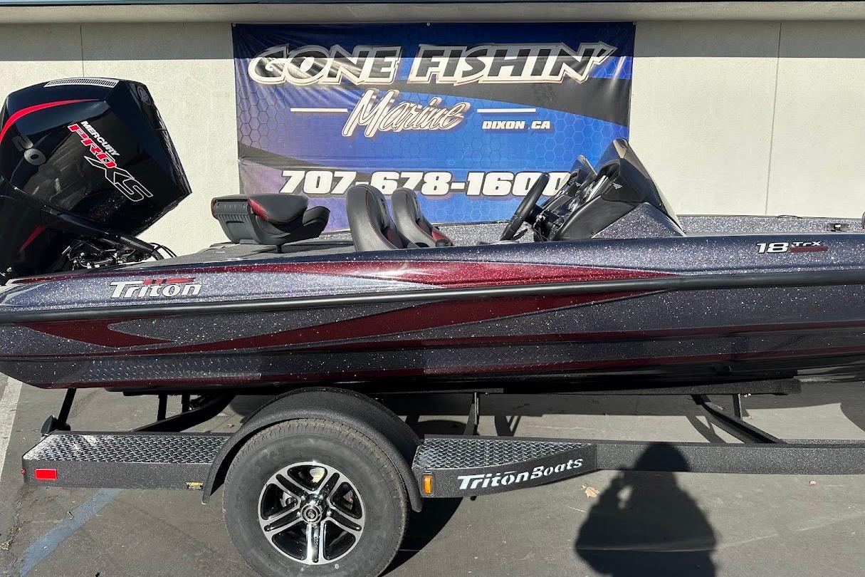 2026 Triton 18 TrX boat on trailer, displayed outdoors with promotional banner.