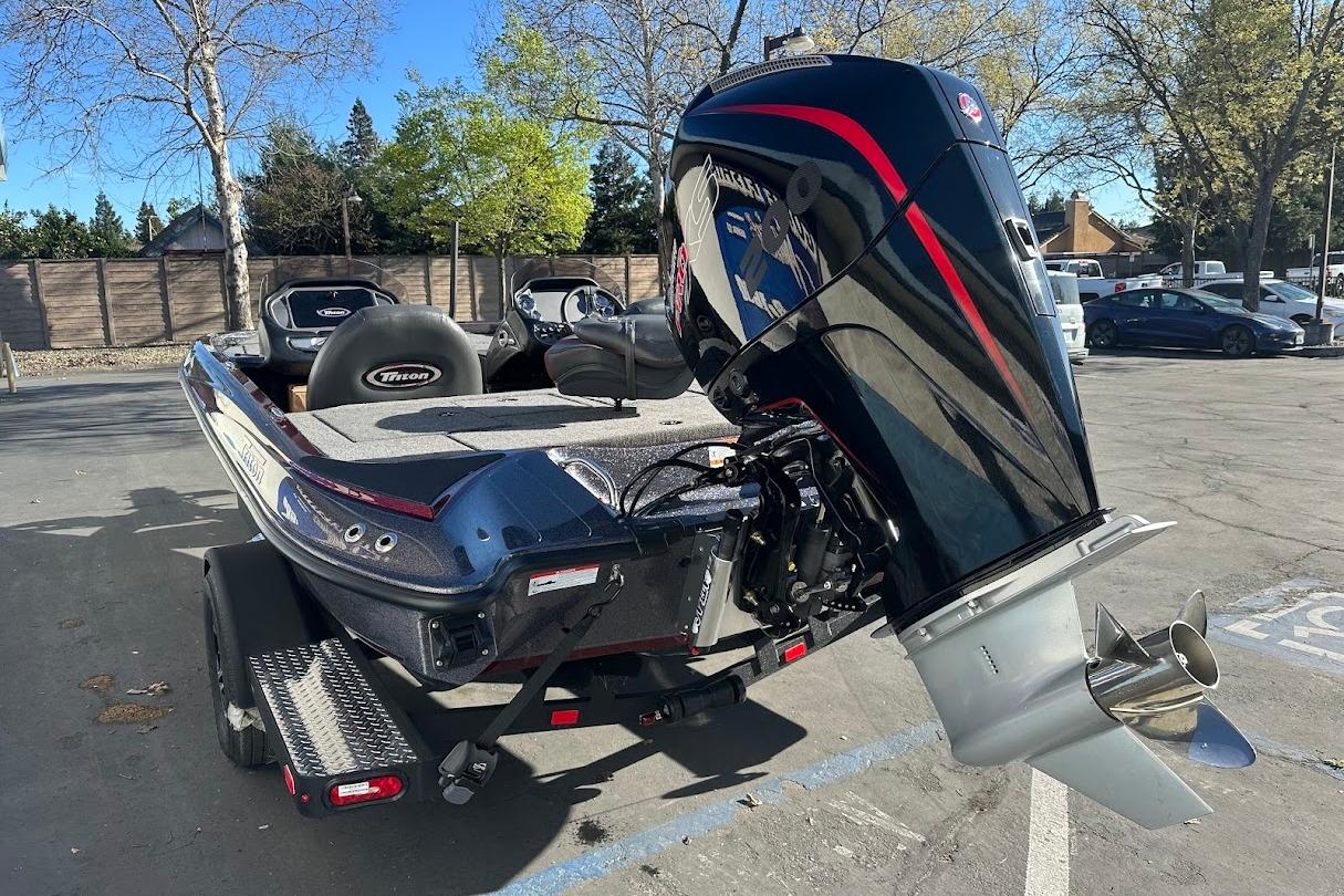 2026 Triton 18 TrX boat with powerful outboard motor in a sunny parking lot.