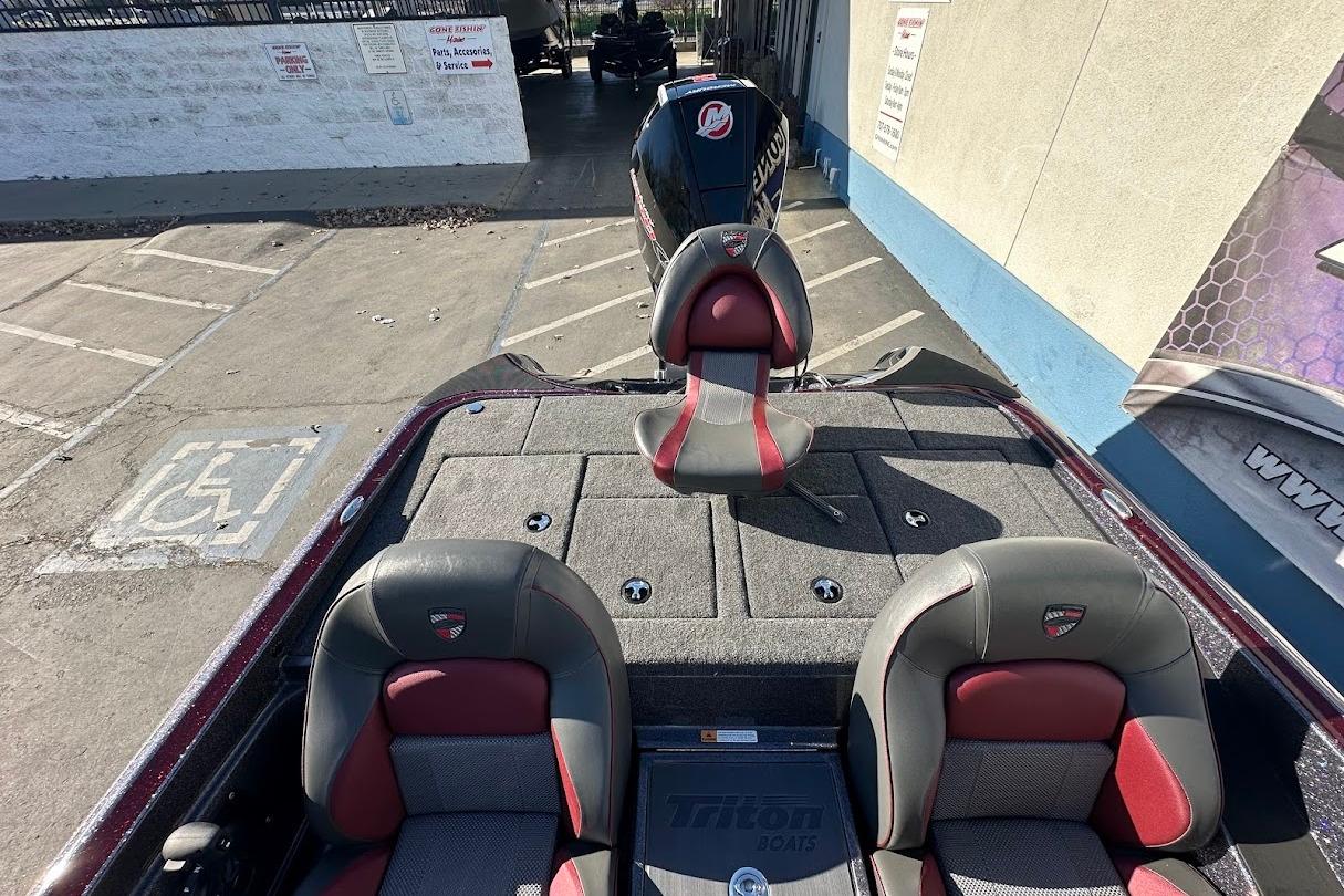 2026 Triton 18 TrX boat interior with red and gray seating, parked outdoors.