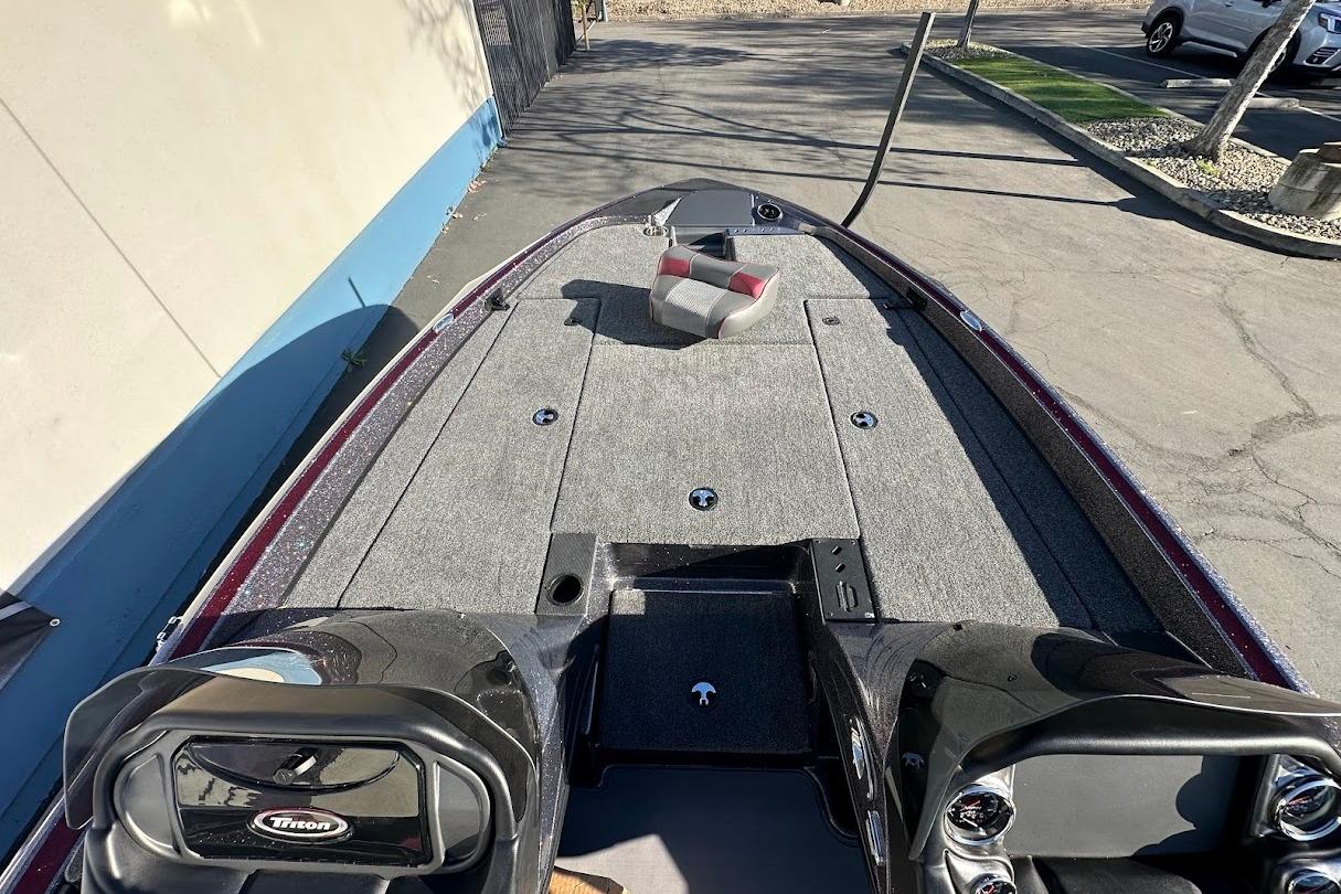 2026 Triton 18 TrX boat deck with gray carpeting and seating, parked outdoors.