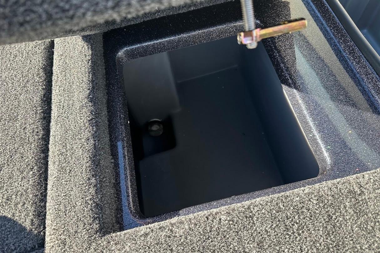 Open storage compartment in 2026 Triton 18 TrX boat, featuring carpeted interior.