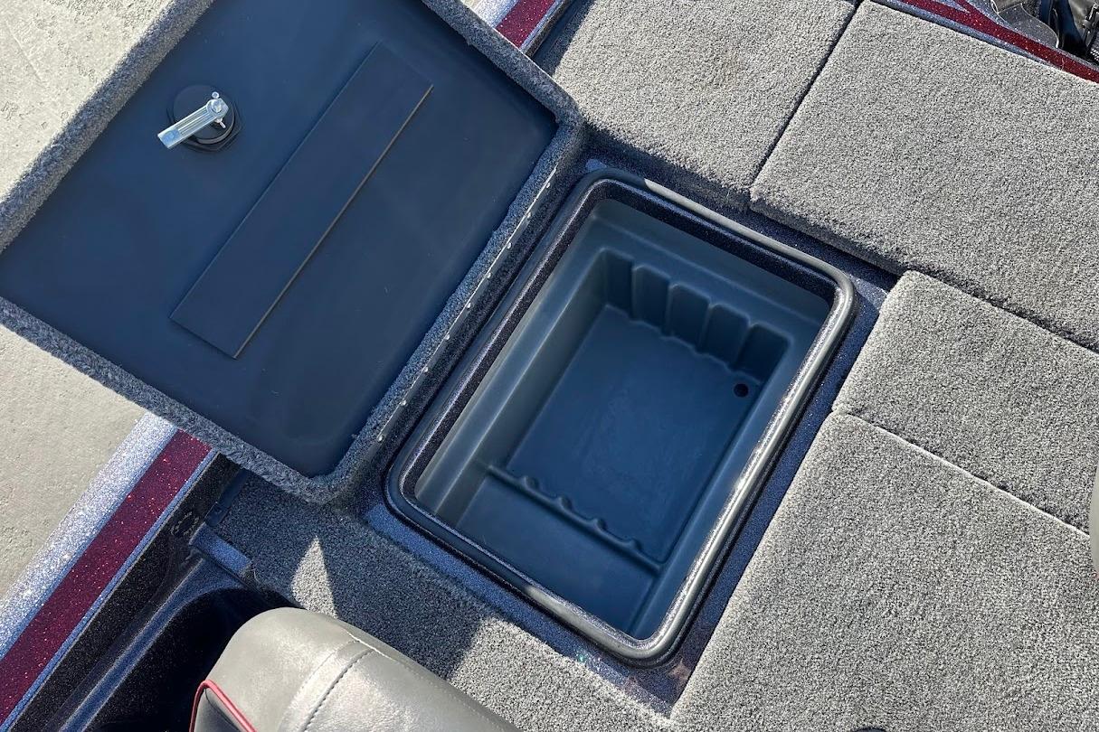 Open storage compartment on 2026 Triton 18 TrX boat with carpeted surface.