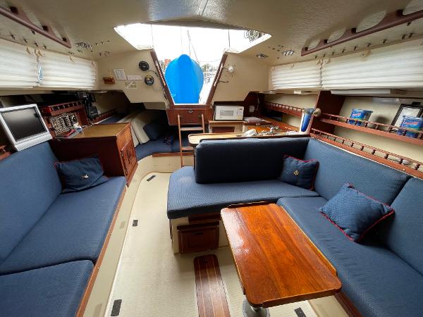 Interior of 1984 Catalina 30 sailboat with blue seating and wooden table.