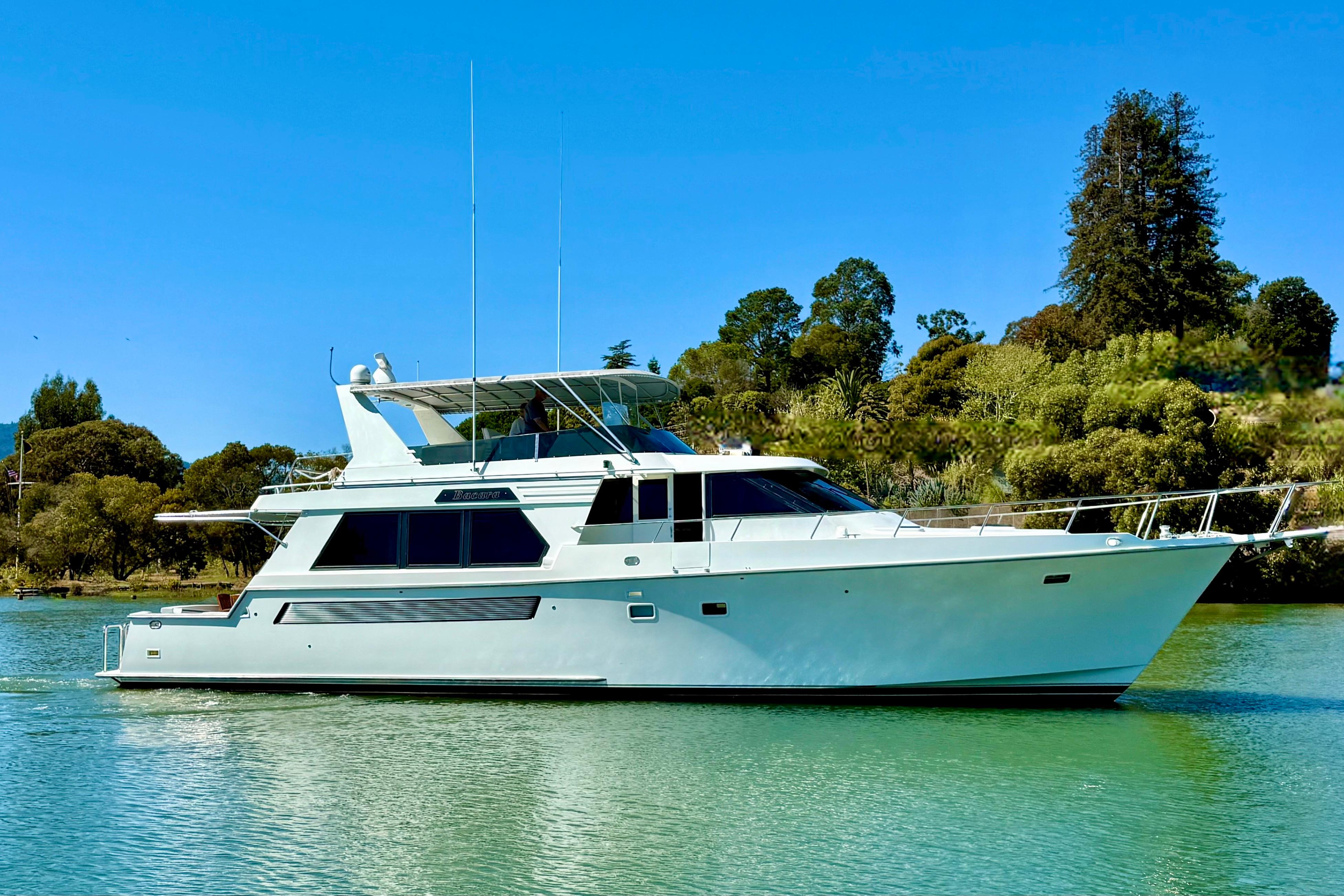 1993 Tollycraft 57 Pilothouse Motor Yacht on serene water, surrounded by lush greenery.