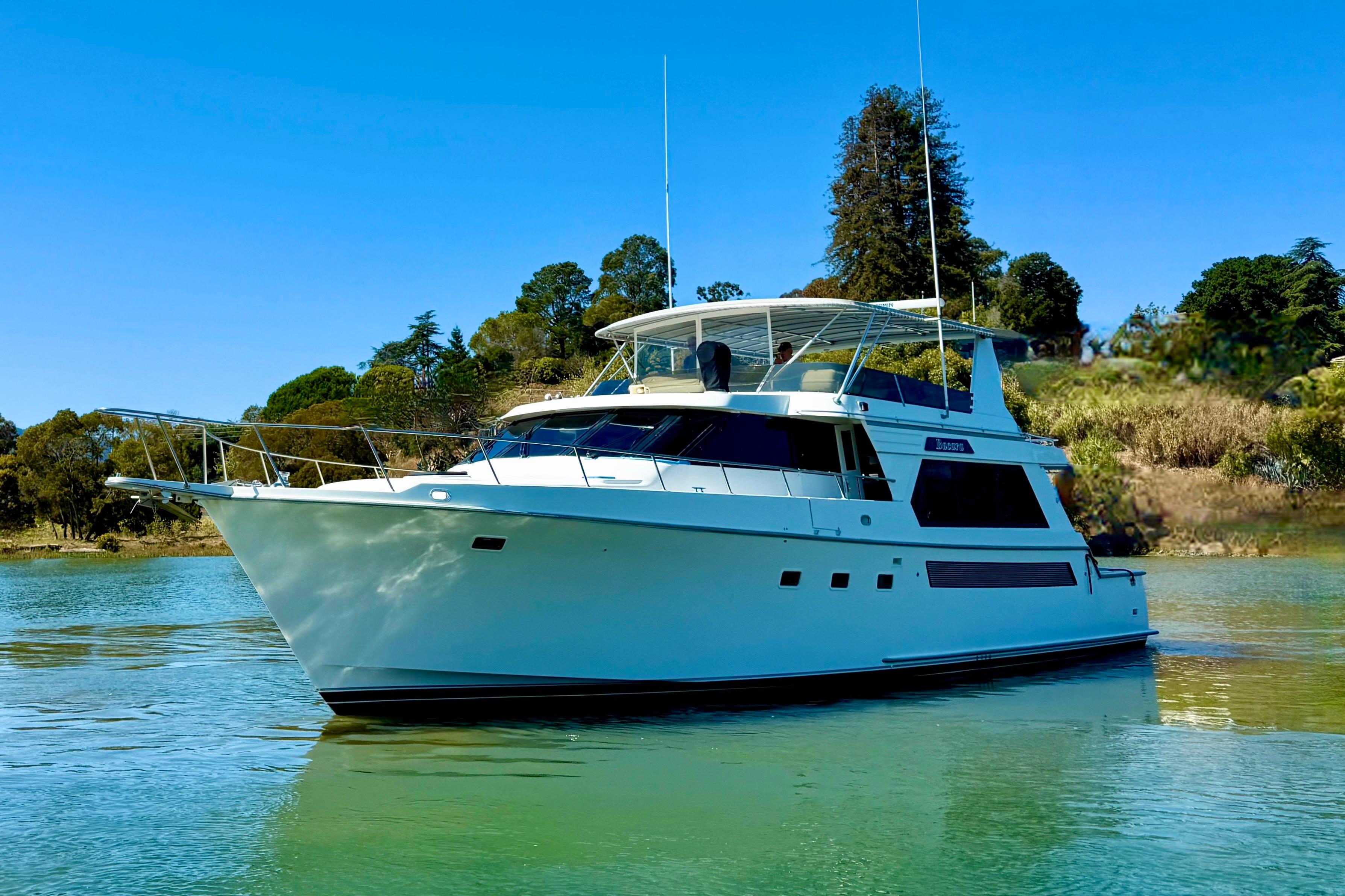 1993 Tollycraft 57 Pilothouse Motor Yacht on serene water, surrounded by lush greenery.