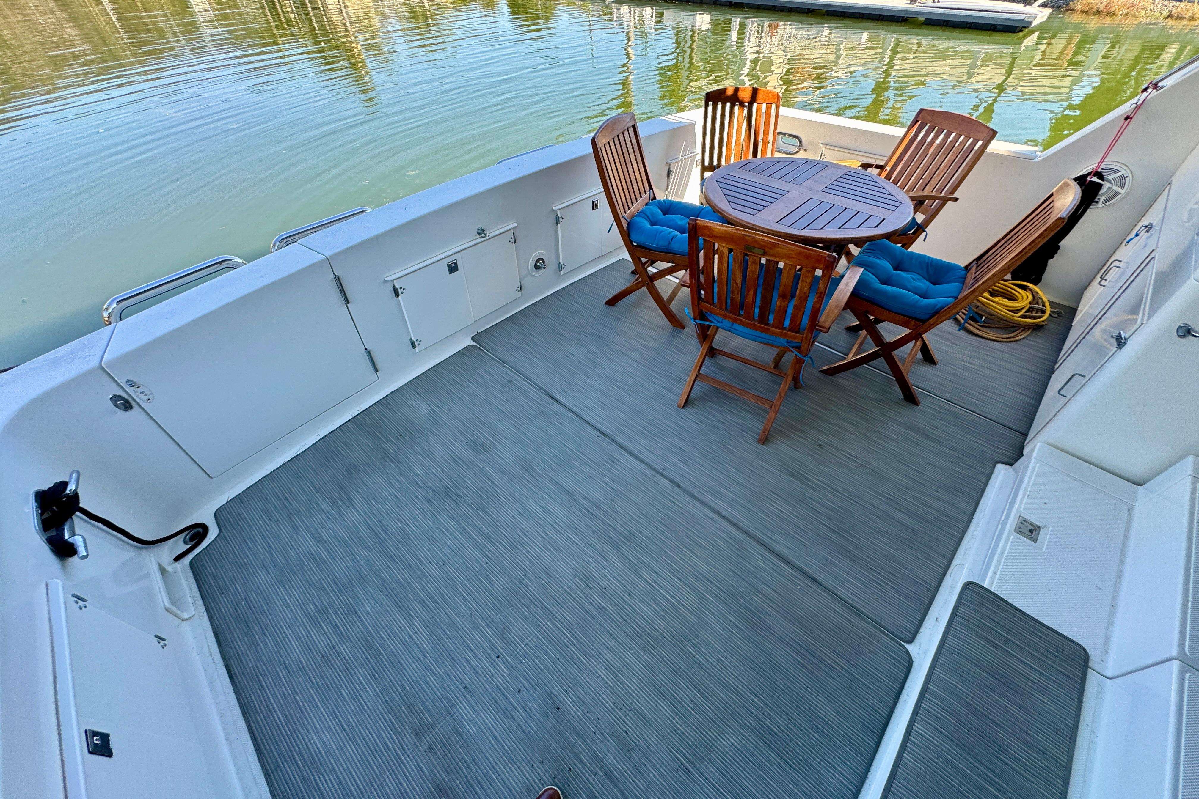 1993 Tollycraft 57 Pilothouse Motor Yacht deck with wooden chairs and table by the water.