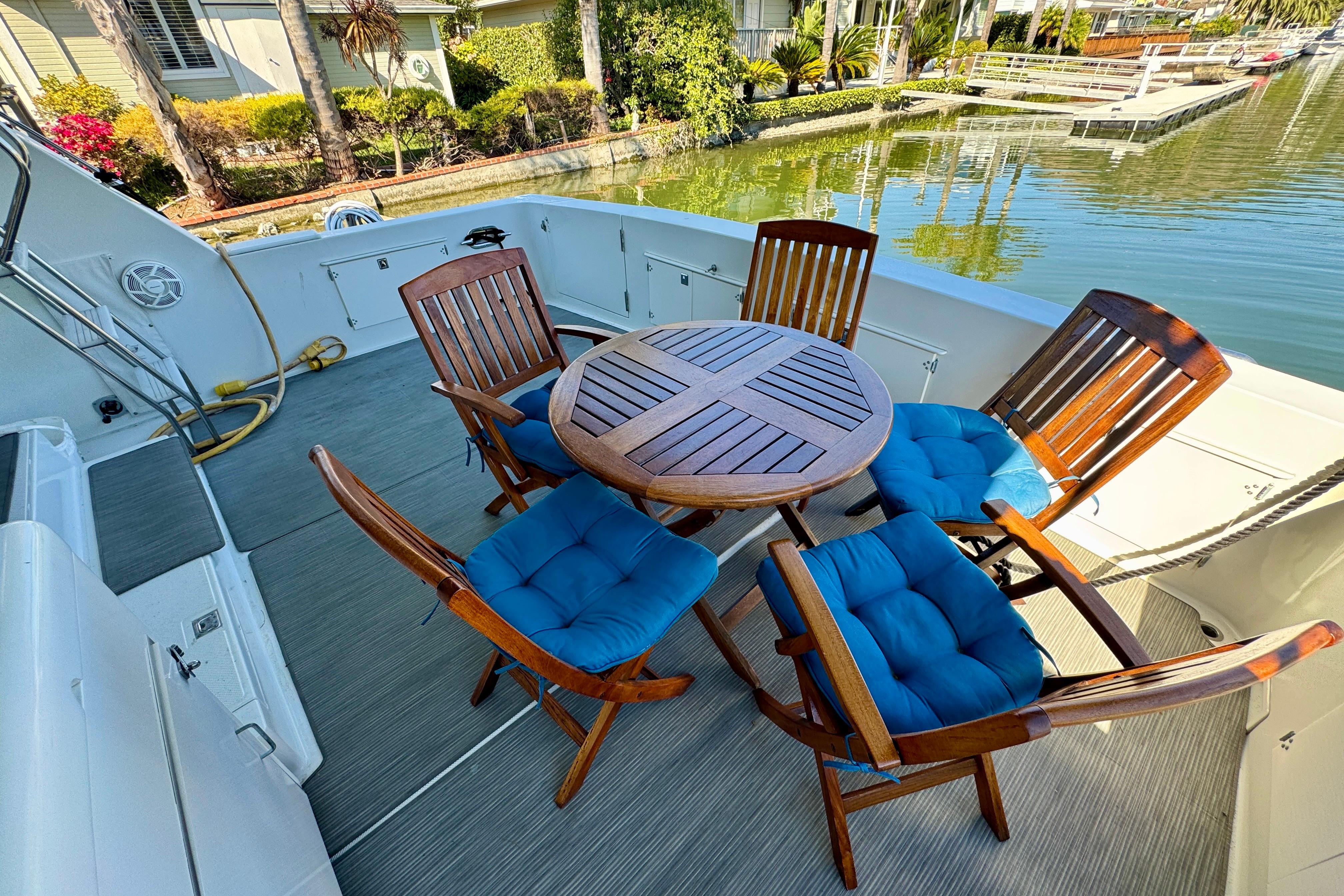 Outdoor seating on 1993 Tollycraft 57 Pilothouse Motor Yacht with blue-cushioned chairs.