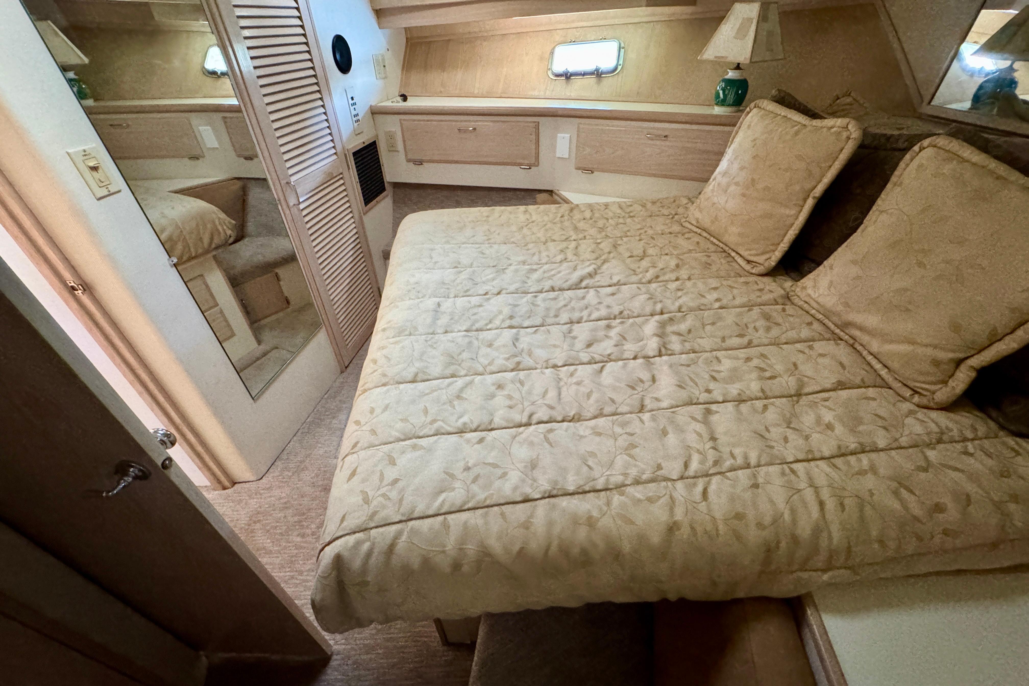Luxurious bedroom interior of 1993 Tollycraft 57 Pilothouse Motor Yacht with cozy bedding.