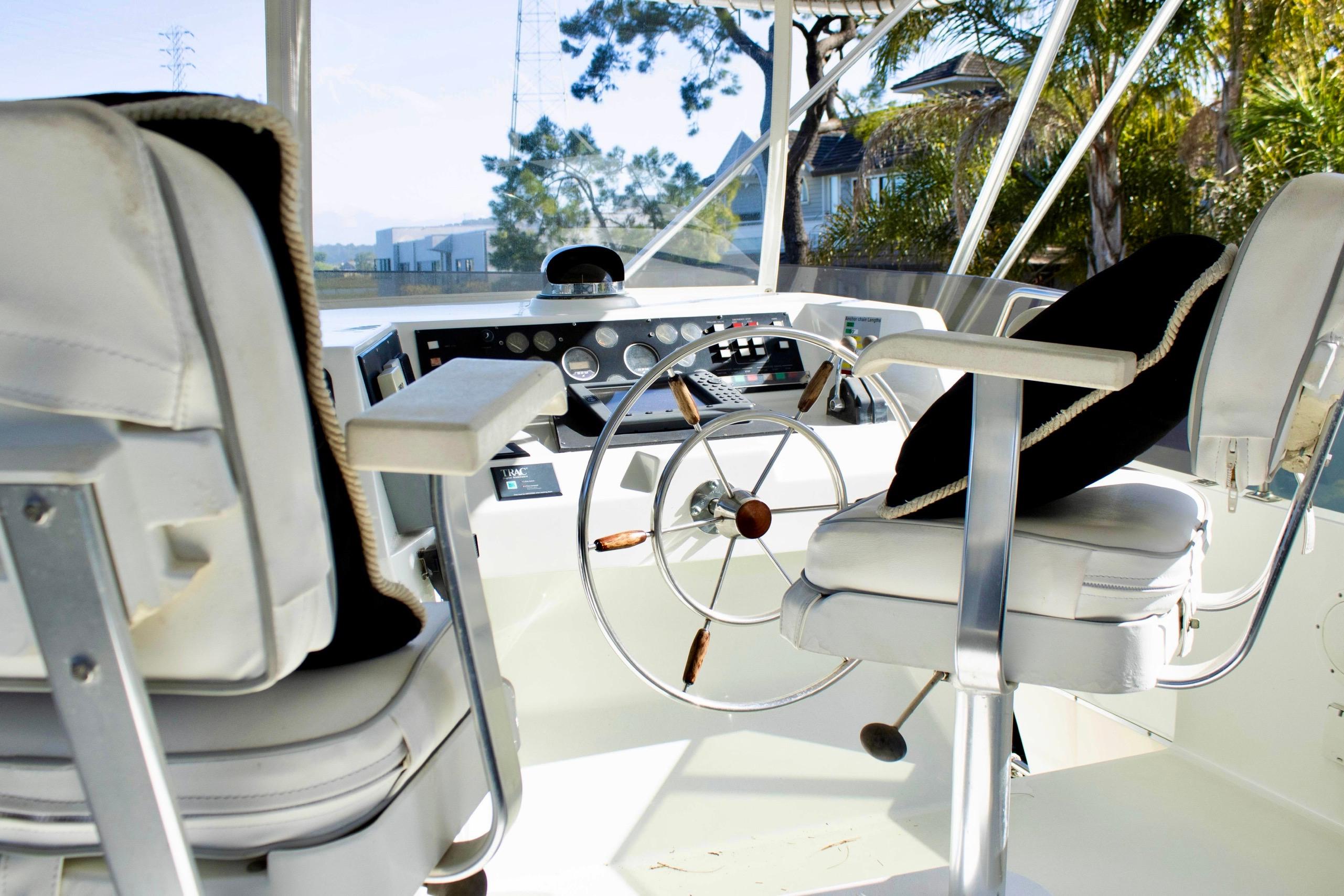 Pilothouse interior of 1993 Tollycraft 57 Motor Yacht with steering wheel and captain's chairs.