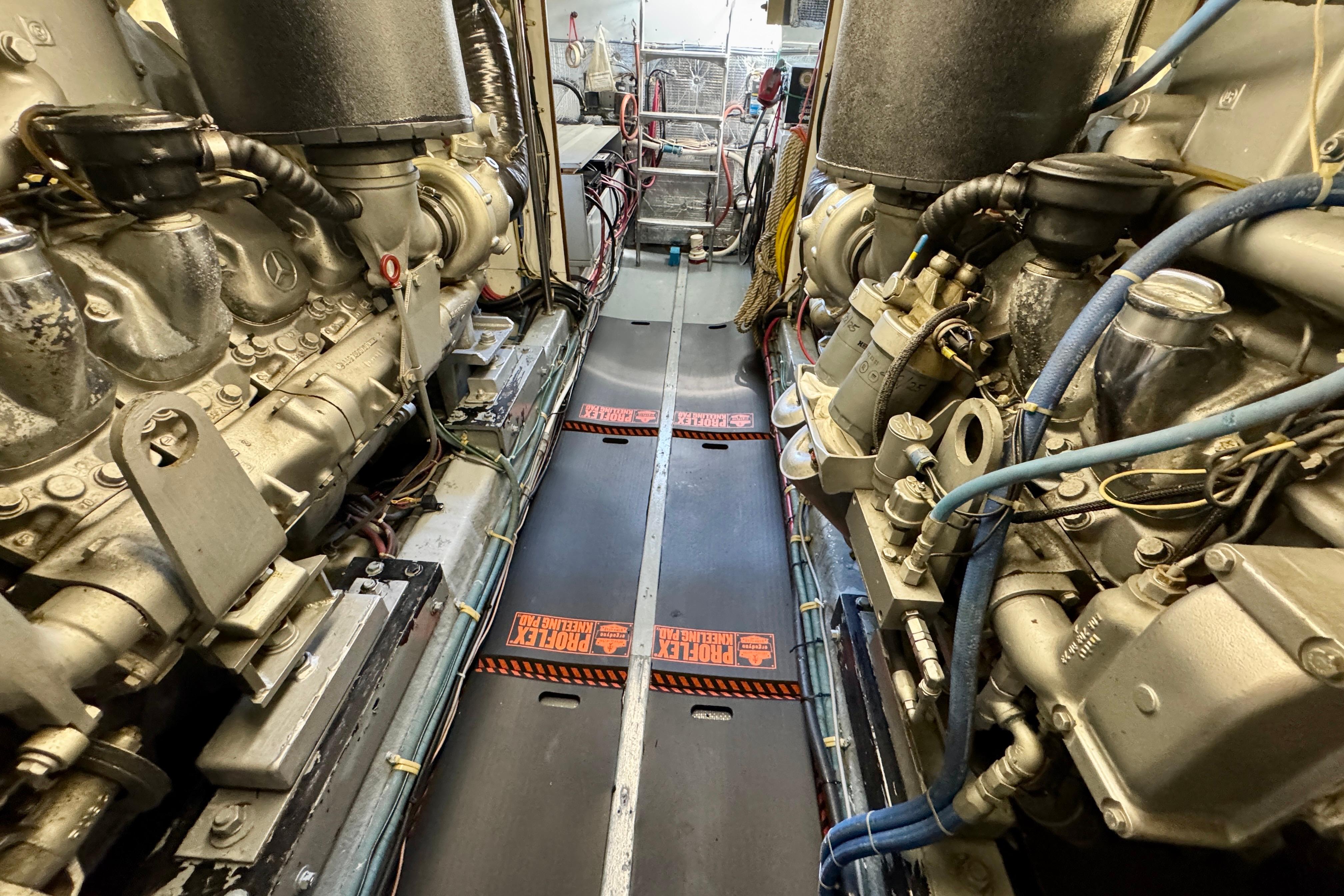 Engine room of 1993 Tollycraft 57 Pilothouse Motor Yacht, showcasing dual engines and mechanical components.