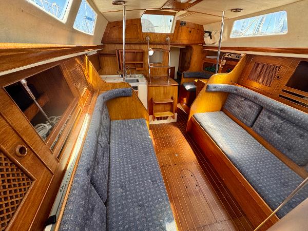 Interior of 1984 Camper & Nicholsons Nicholson 35 sailboat with wooden furnishings and blue seating.