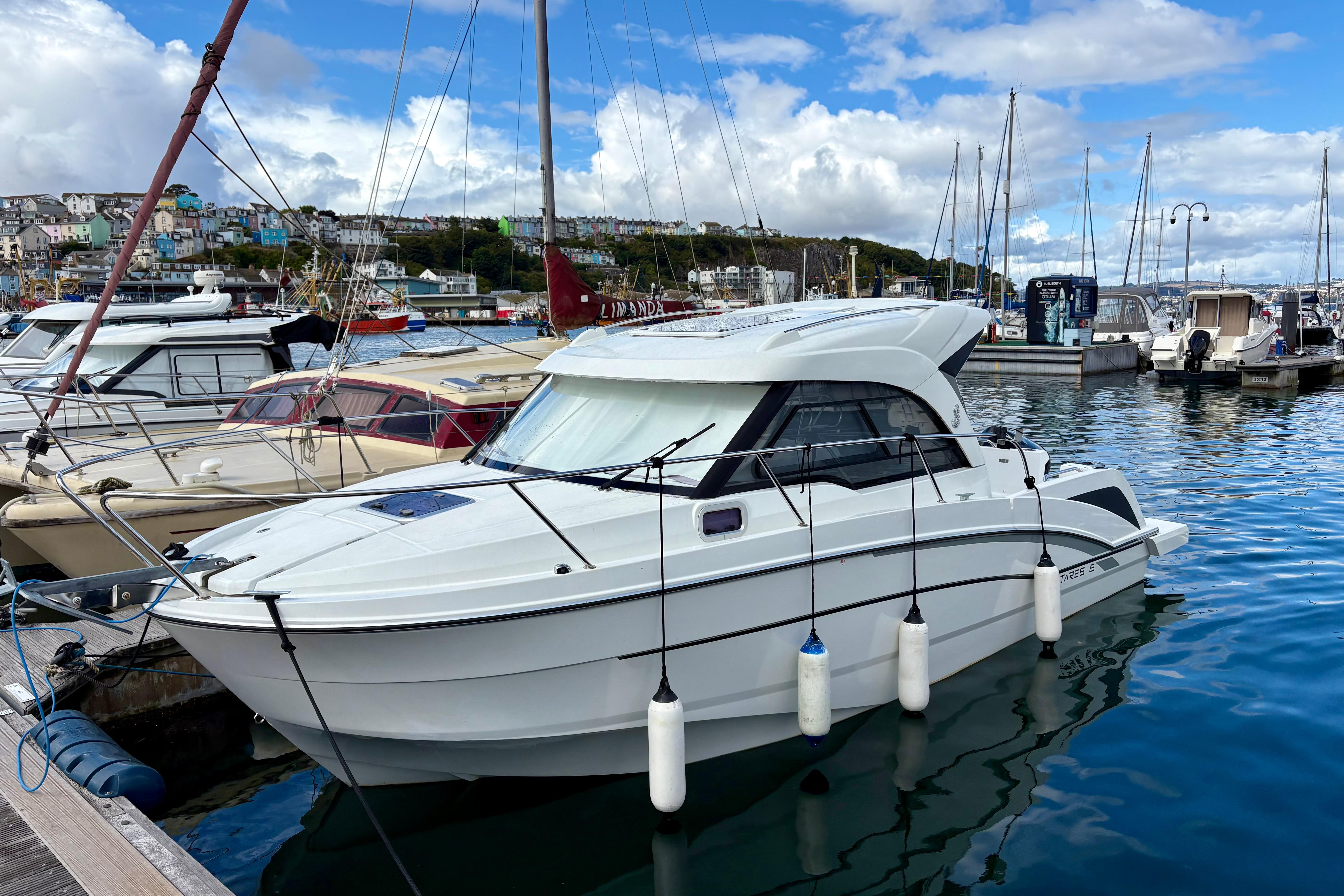 2019 Beneteau Antares 8 docked in a marina, surrounded by other boats.