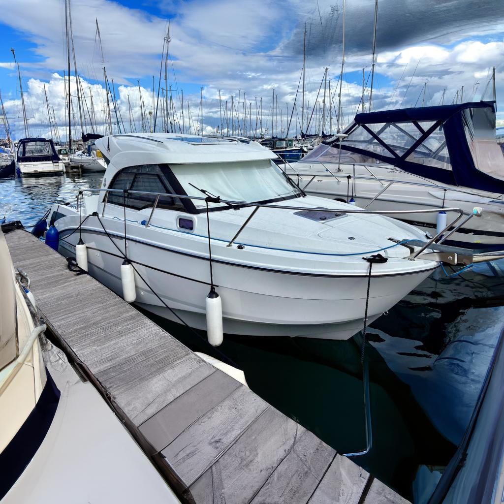 2019 Beneteau Antares 8 docked in a marina, surrounded by other boats.