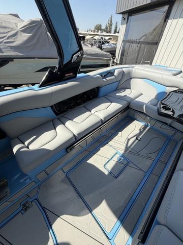 2025 Centurion Fe25 boat interior with blue and gray seating, docked near a building.