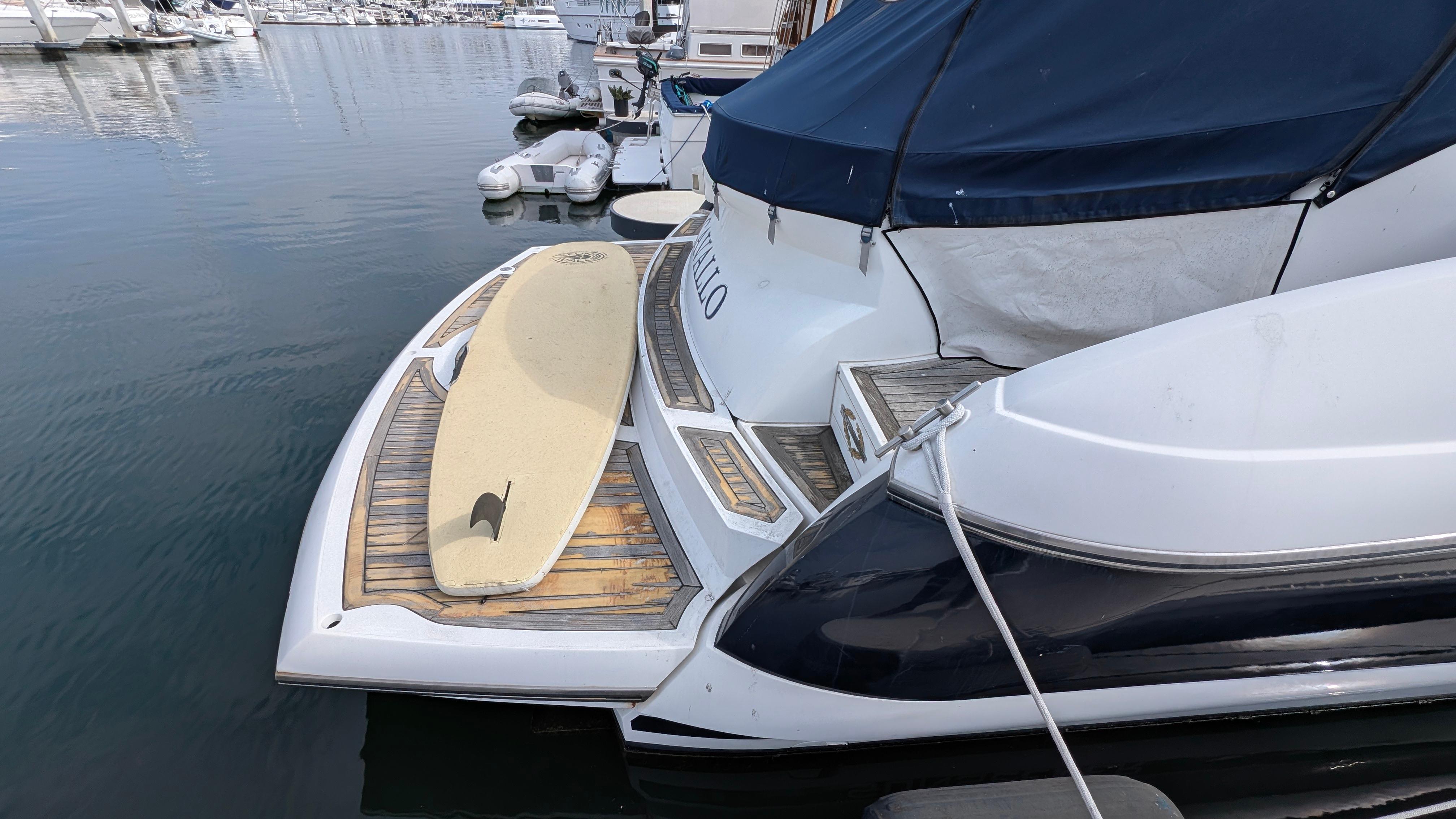 2004 Sunseeker Portofino yacht with surfboard on deck, docked in marina.