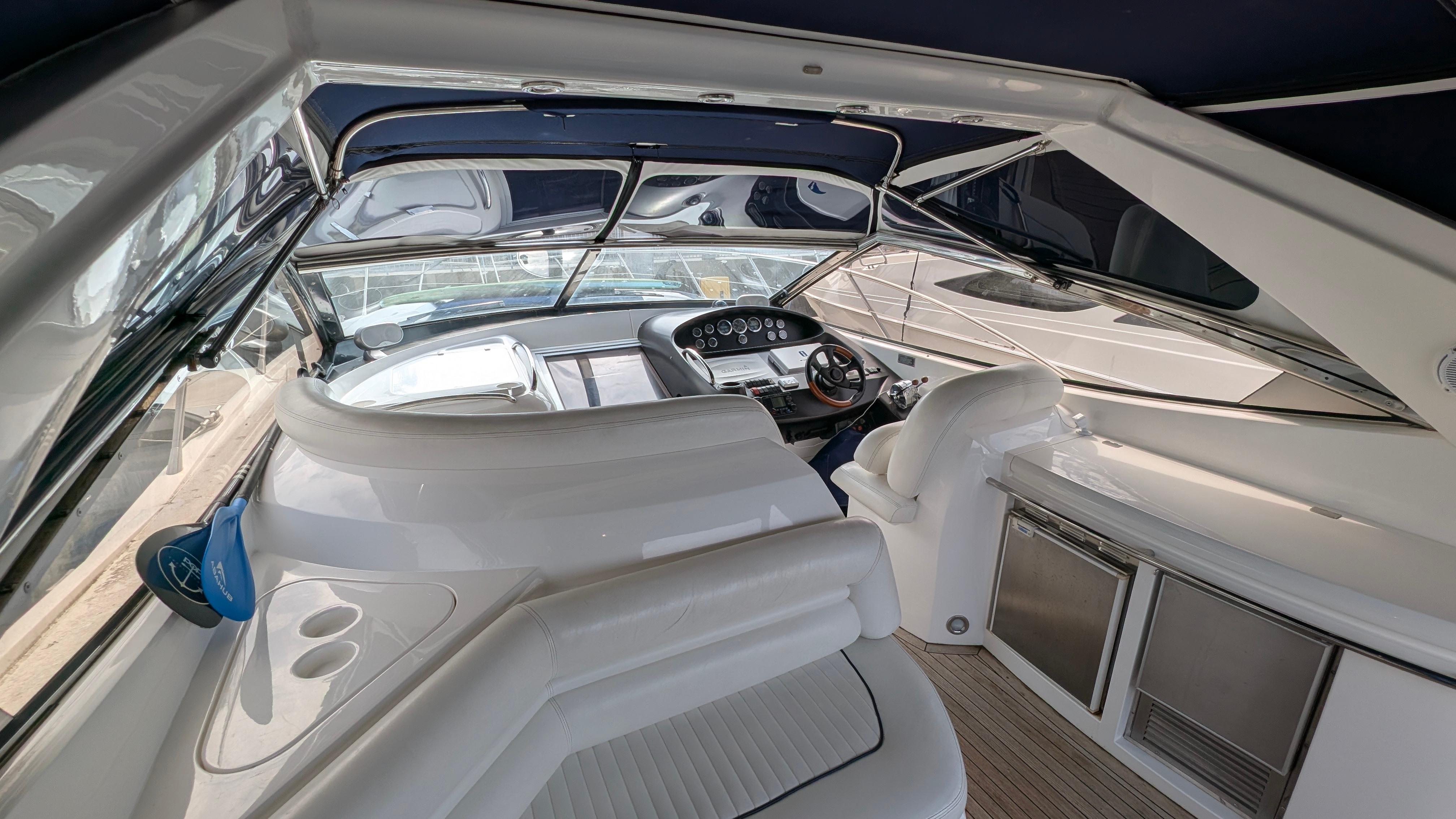 2004 Sunseeker Portofino yacht interior with sleek white seating and modern dashboard.