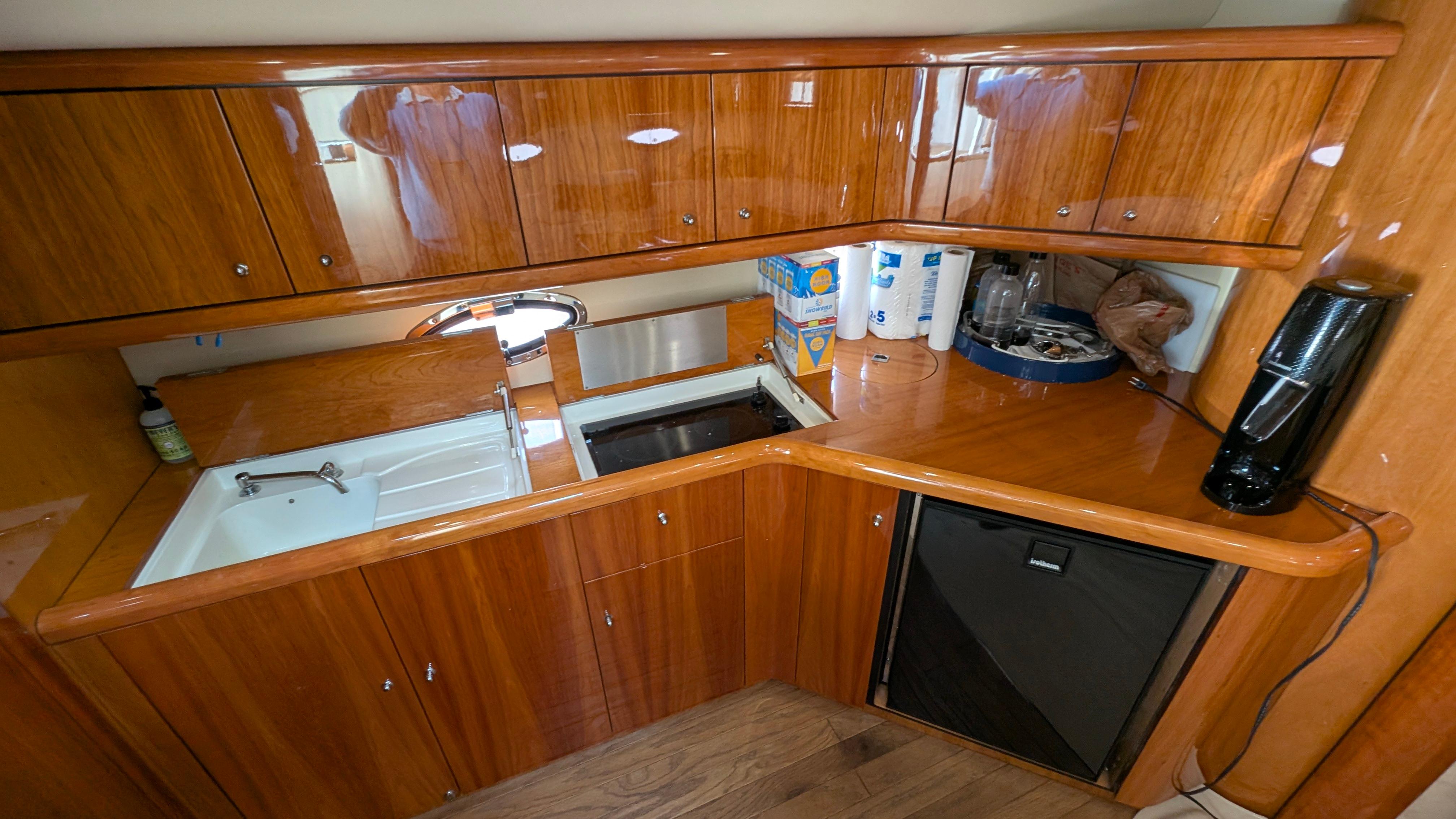 2004 Sunseeker Portofino yacht kitchen with wooden cabinets, sink, and mini fridge.