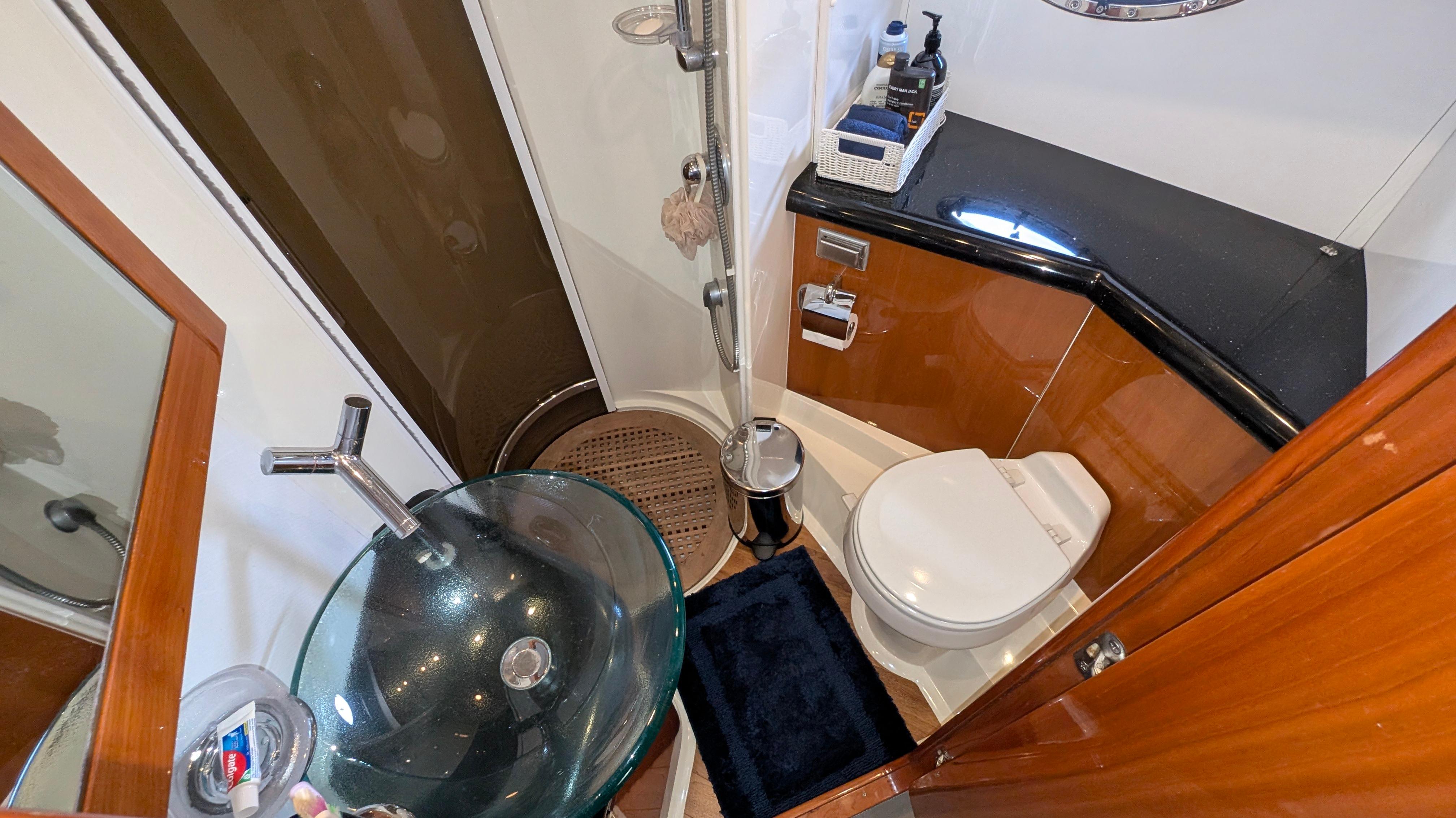 Luxurious 2004 Sunseeker Portofino yacht bathroom with glass sink and modern fixtures.