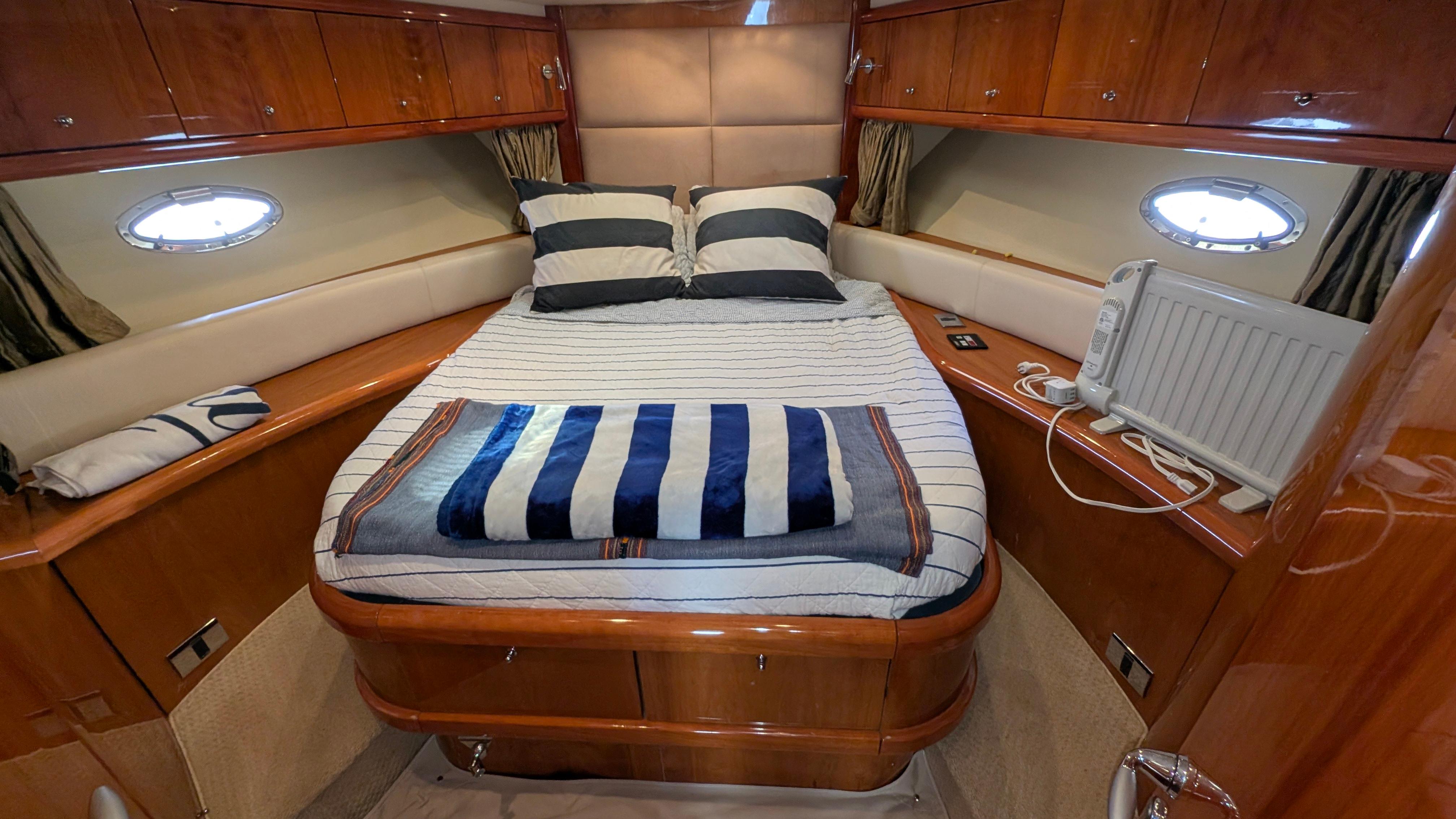 Luxurious cabin interior of 2004 Sunseeker Portofino yacht with cozy bed and elegant wood finish.