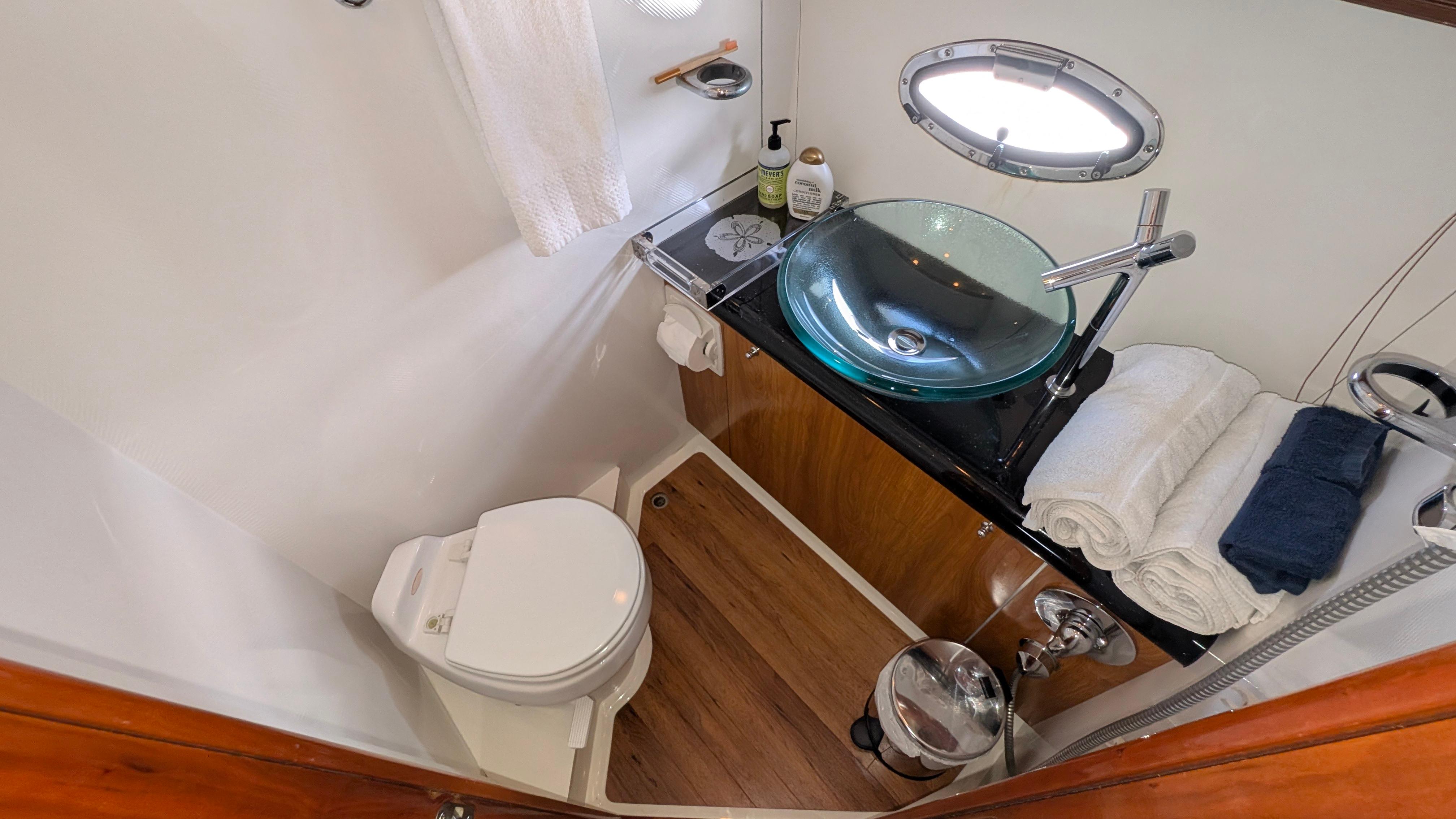 Luxurious 2004 Sunseeker Portofino yacht bathroom with modern glass sink and wooden accents.