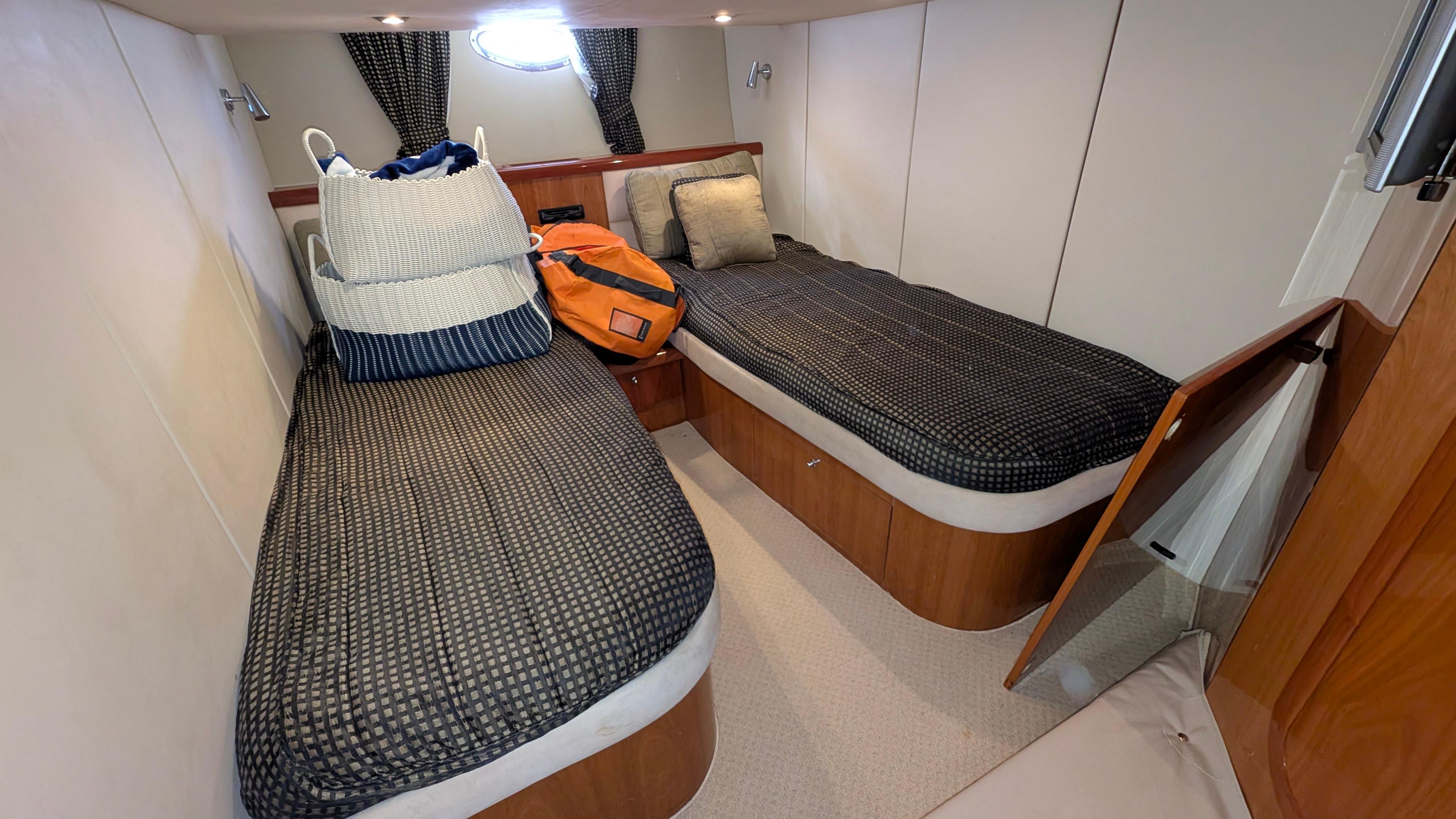 2004 Sunseeker Portofino cabin with twin beds, cozy decor, and storage bags.