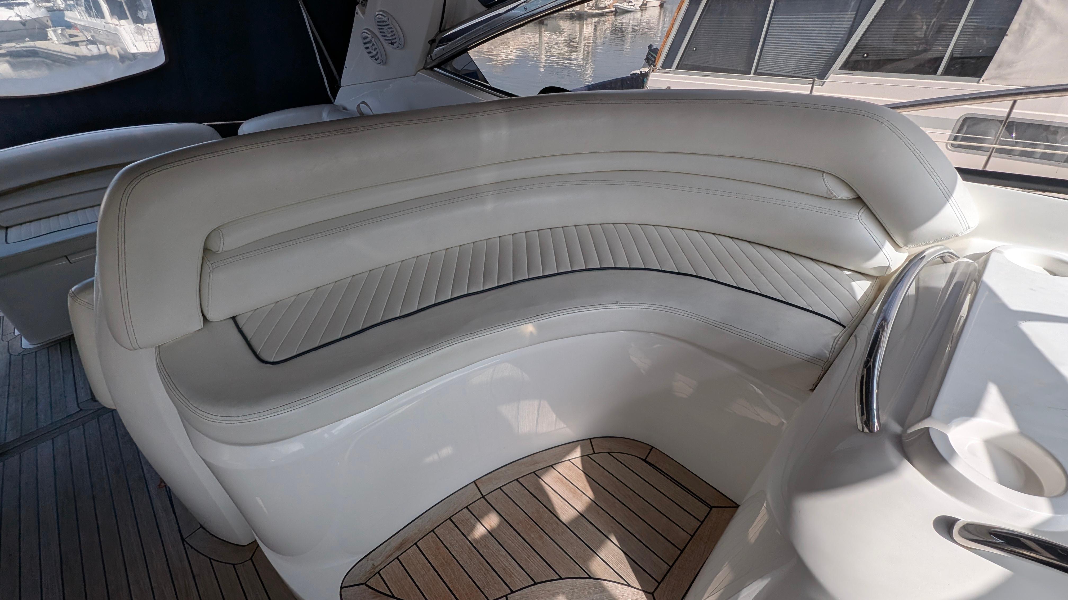 Luxury seating on 2004 Sunseeker Portofino yacht with elegant white upholstery and wooden flooring.