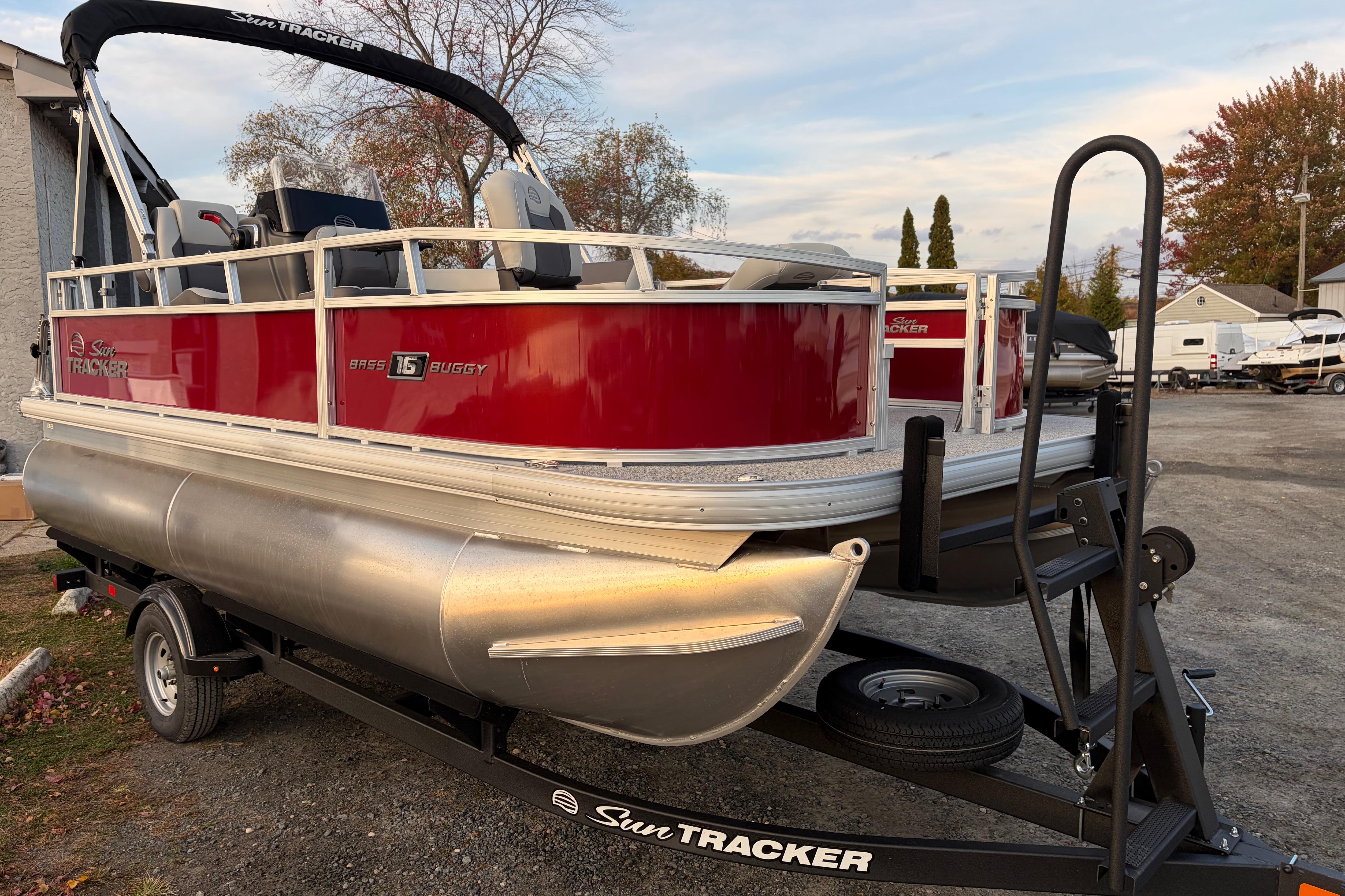 2026 Sun Tracker Bass Buggy 16 XL Select pontoon boat on trailer, red and silver design.