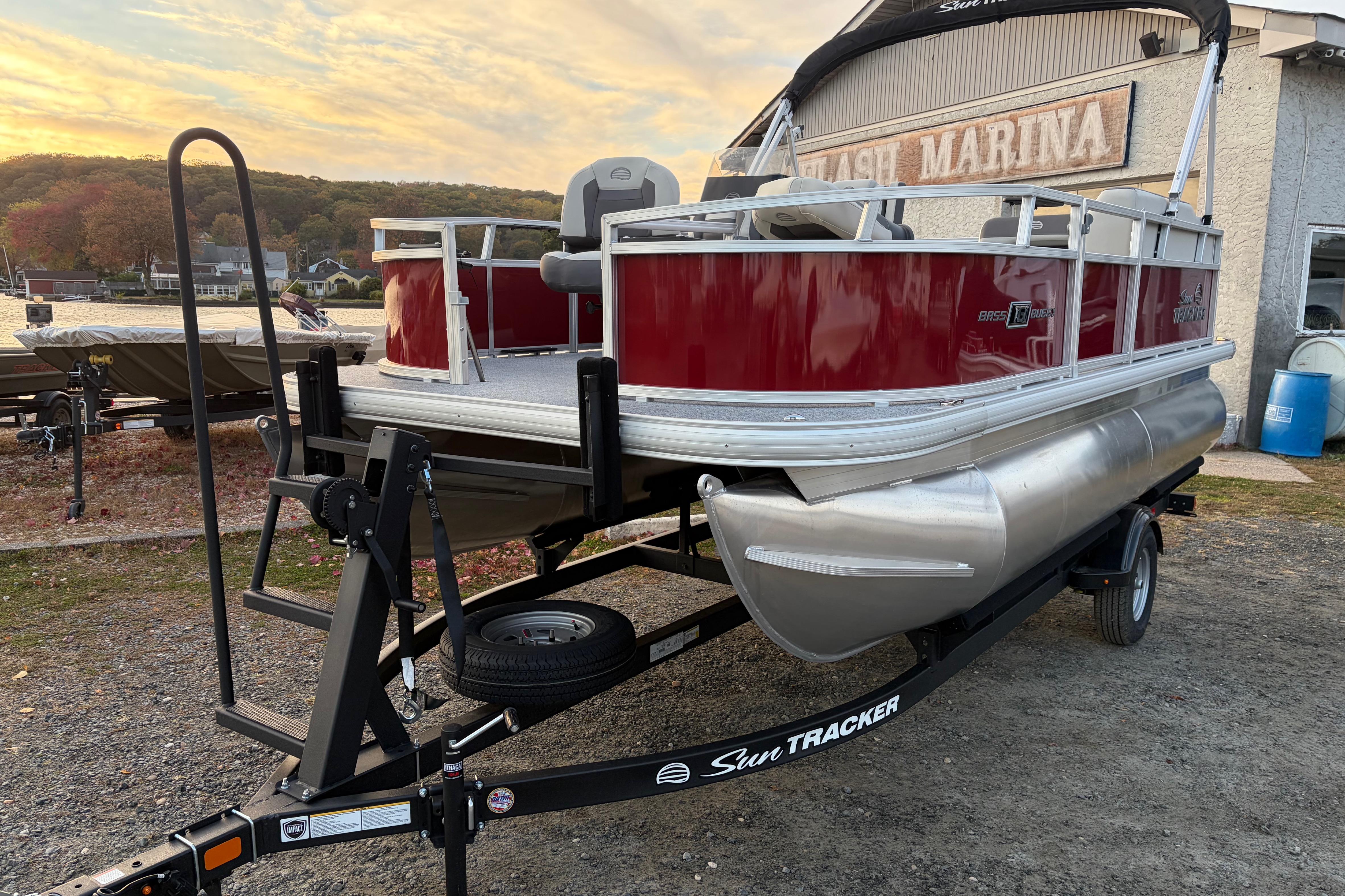 2026 Sun Tracker Bass Buggy 16 XL Select pontoon boat on trailer at marina.