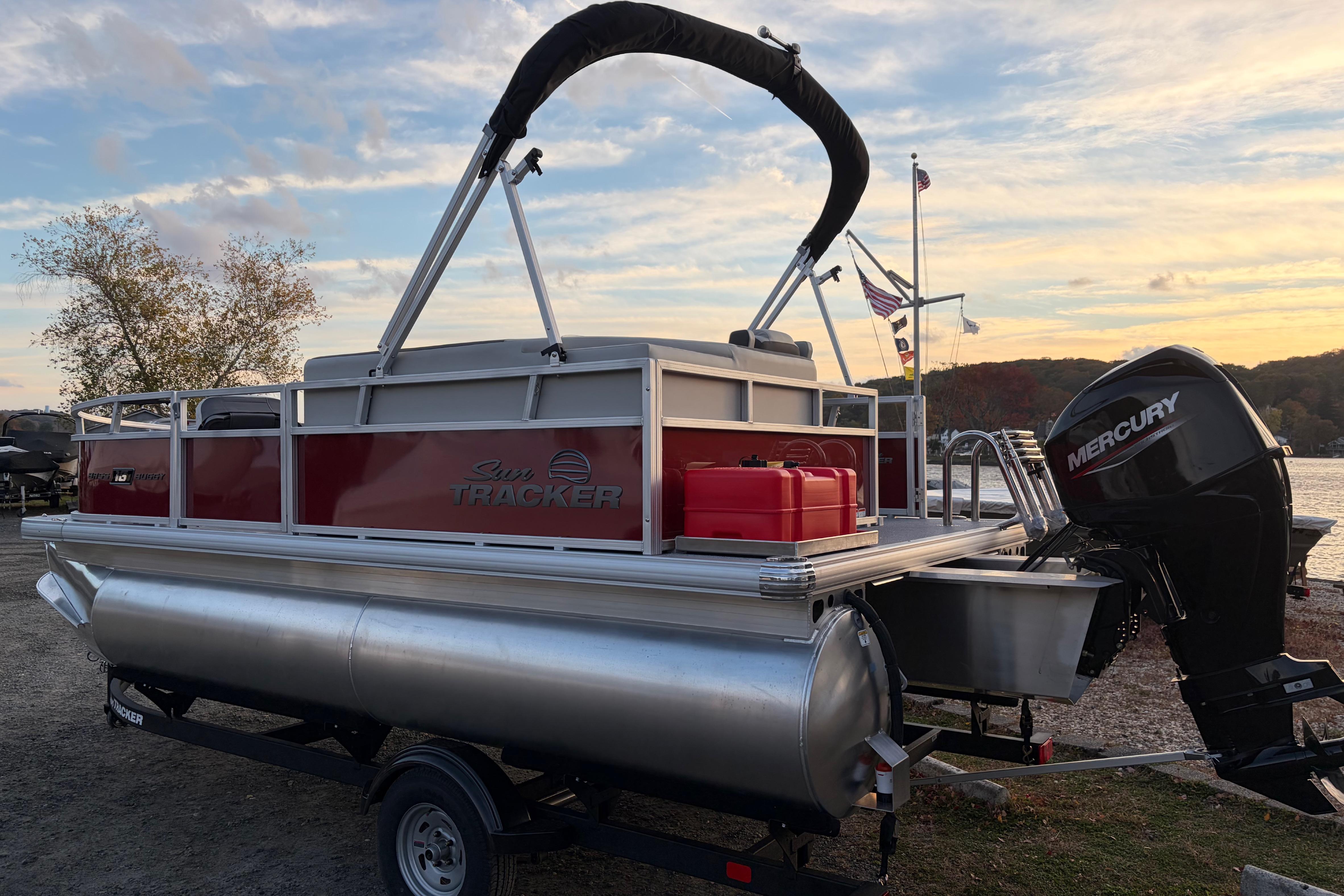 2026 Sun Tracker Bass Buggy 16 XL Select pontoon boat with Mercury outboard motor at sunset.
