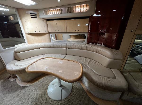 Luxurious interior of 2000 Sea Ray 380 Sundancer with curved seating and wooden table.