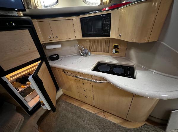 Interior of a 2000 Sea Ray 380 Sundancer yacht kitchen with fridge, stove, and microwave.