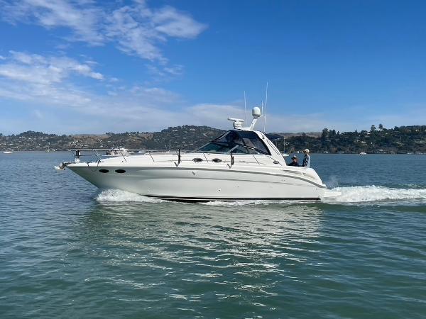 2000 Sea Ray 380 Sundancer cruising on calm waters under a clear blue sky.