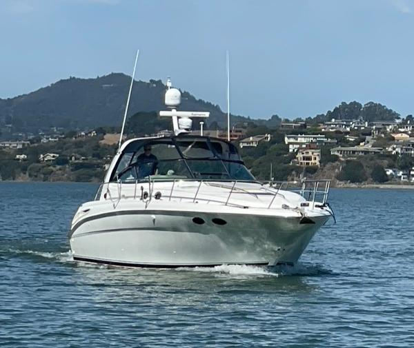 2000 Sea Ray 380 Sundancer cruising on a scenic lake with hills in the background.