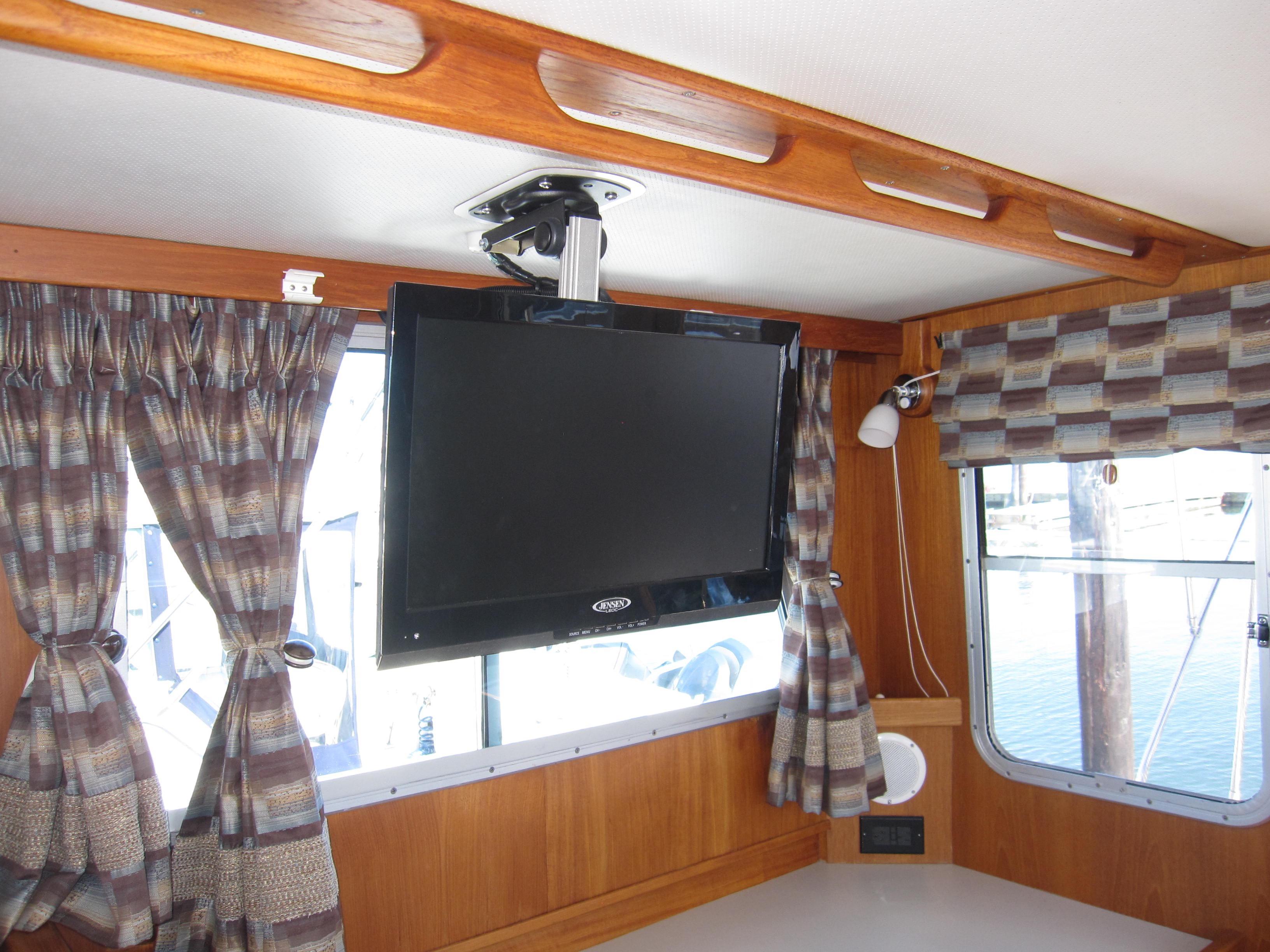 Interior of 1990 Blue Seas 31 Hardtop Cruiser with mounted TV and window curtains.