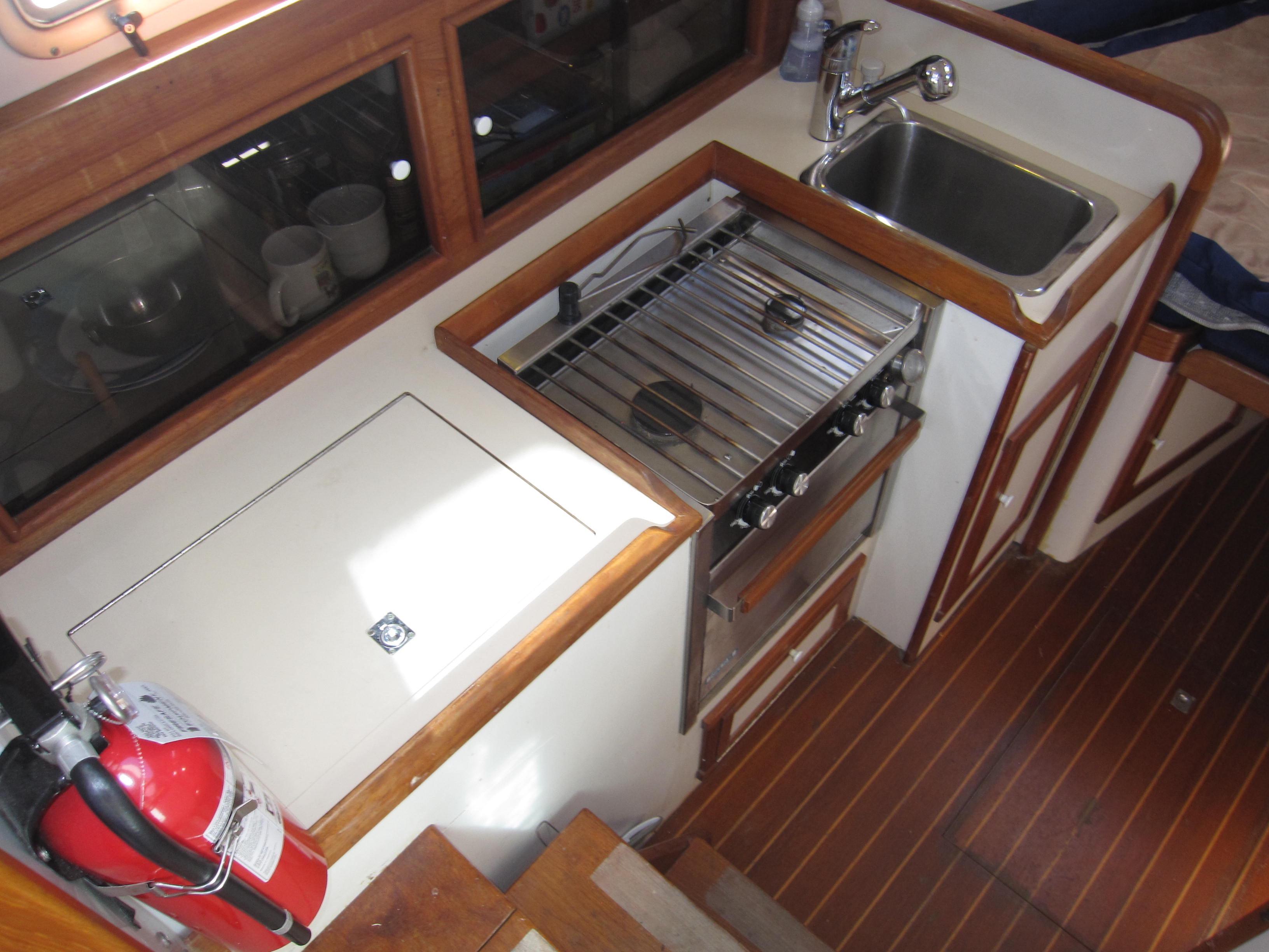 1990 Blue Seas 31 Hardtop Cruiser galley with stove, sink, and fire extinguisher.