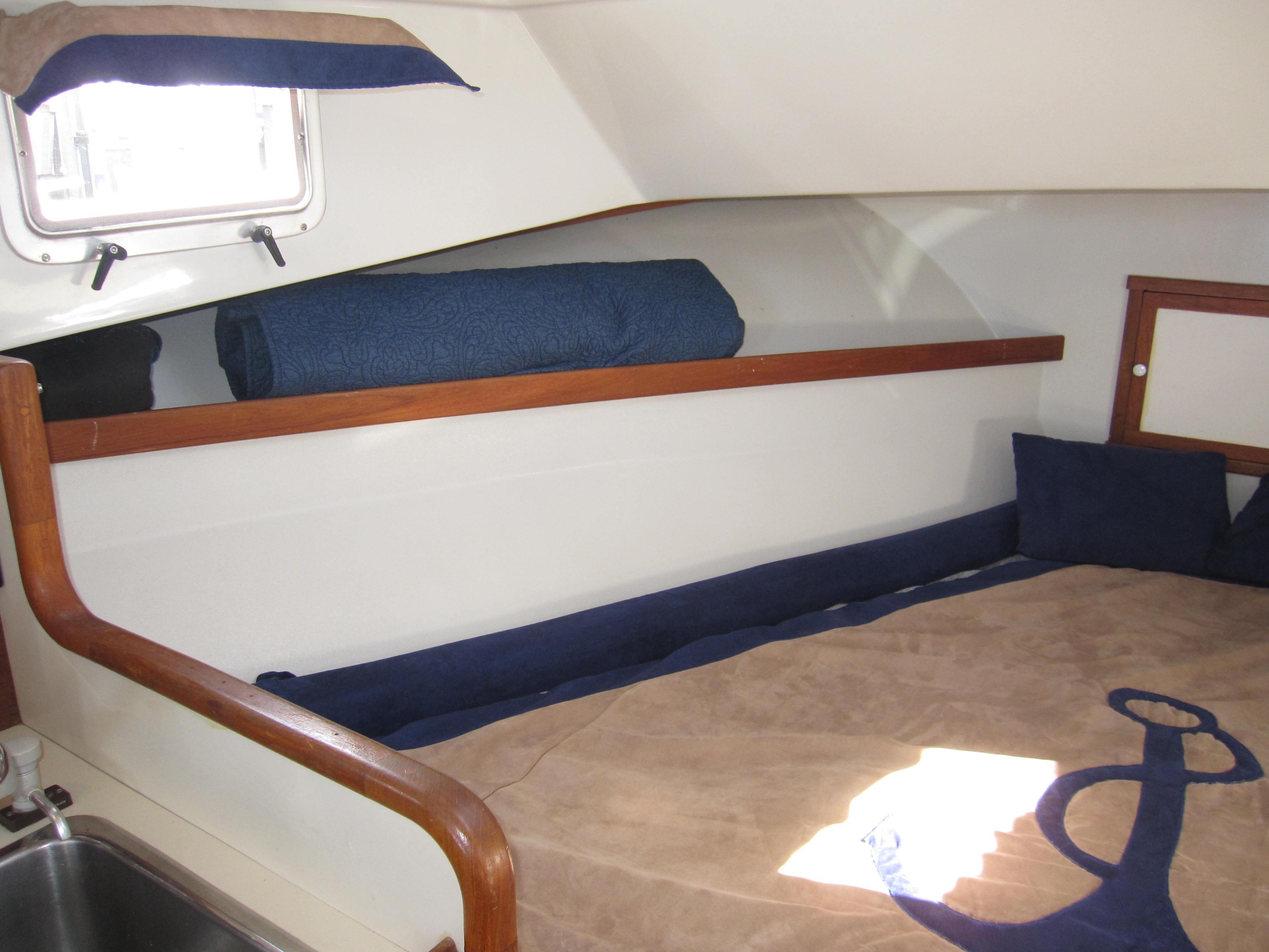 Interior cabin of a 1990 Blue Seas 31 Hardtop Cruiser with bed and porthole.