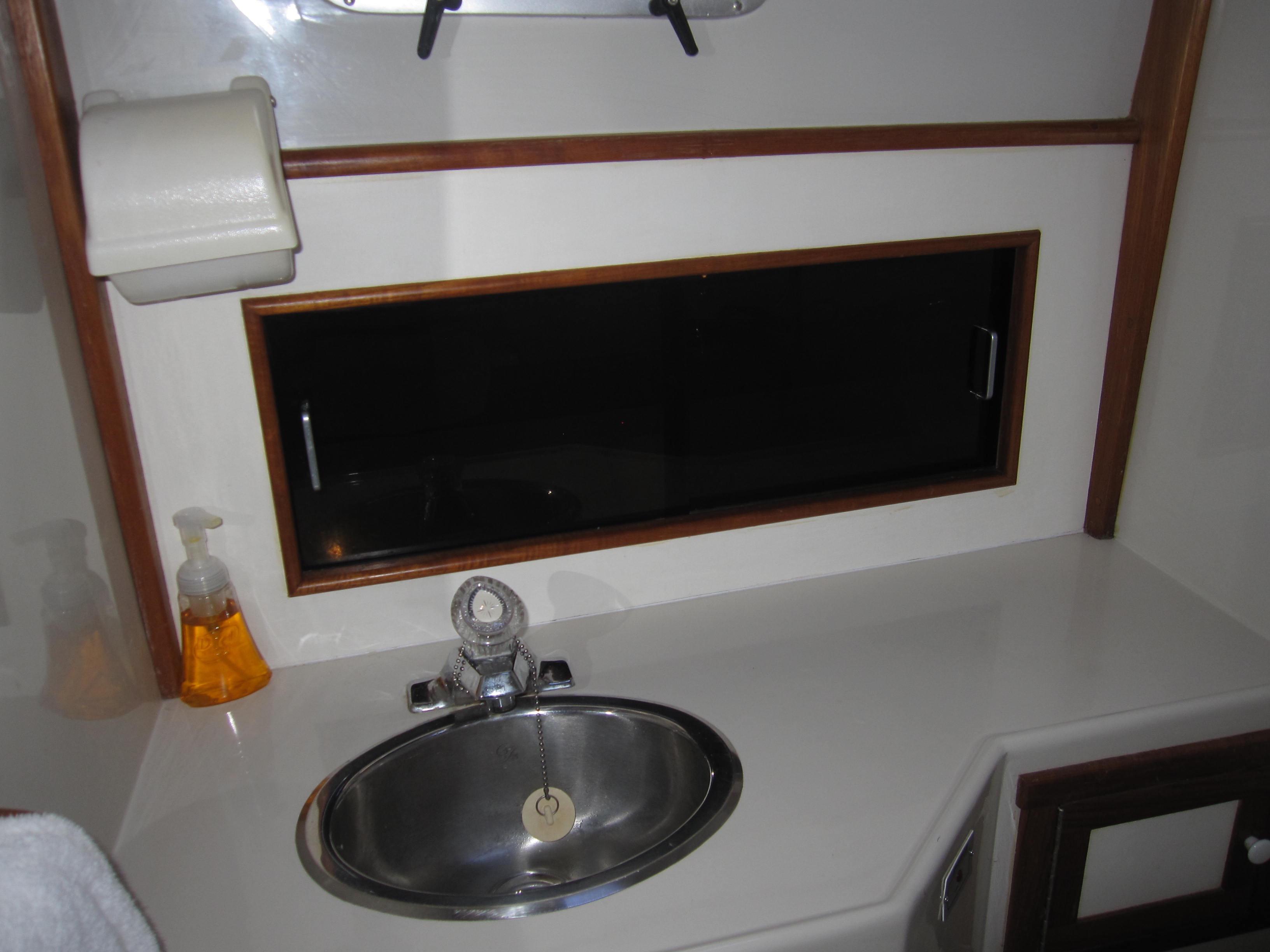 1990 Blue Seas 31 Hardtop Cruiser bathroom sink with window and soap dispenser.