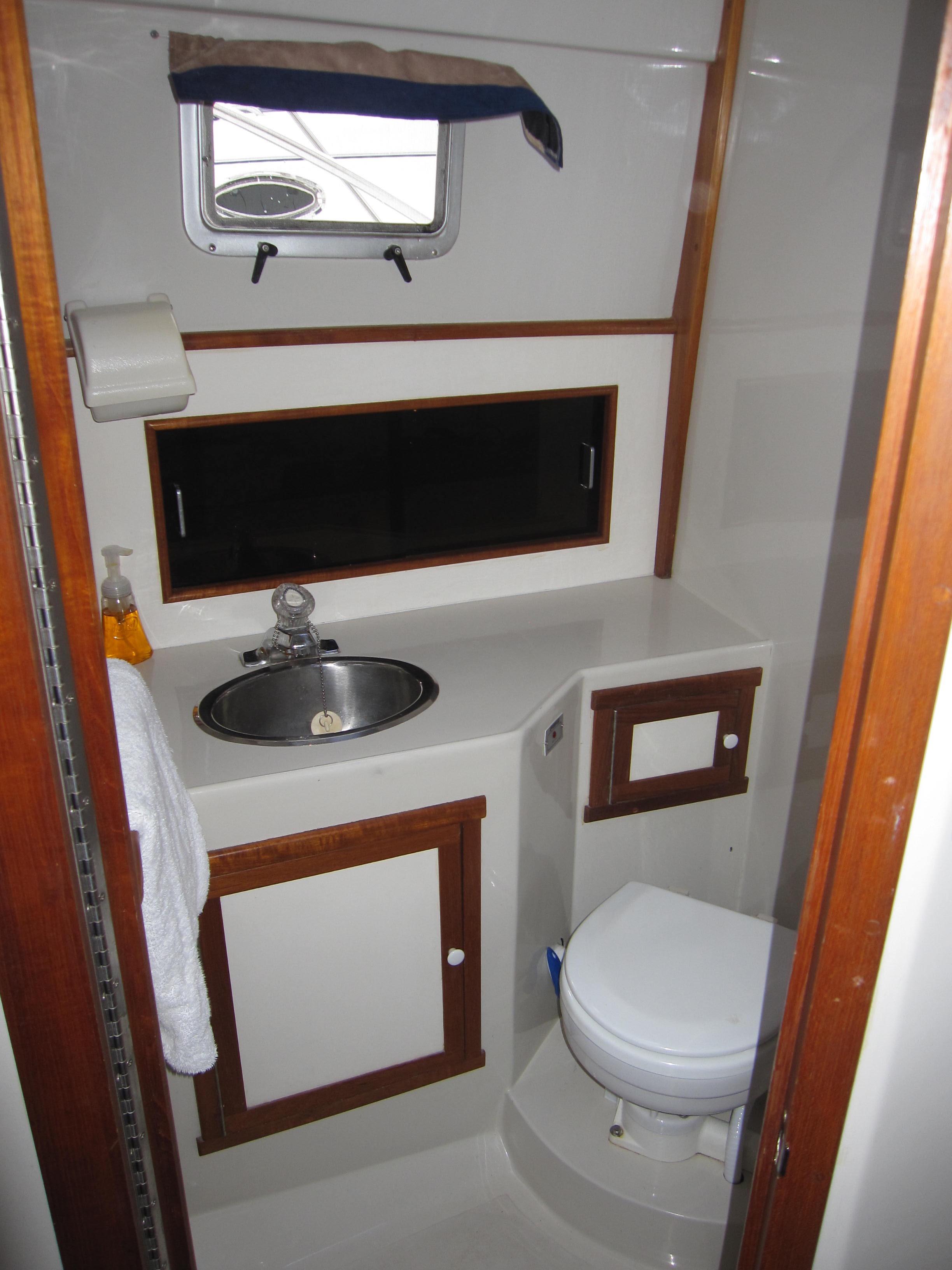 1990 Blue Seas 31 Hardtop Cruiser bathroom with sink, toilet, and storage cabinets.