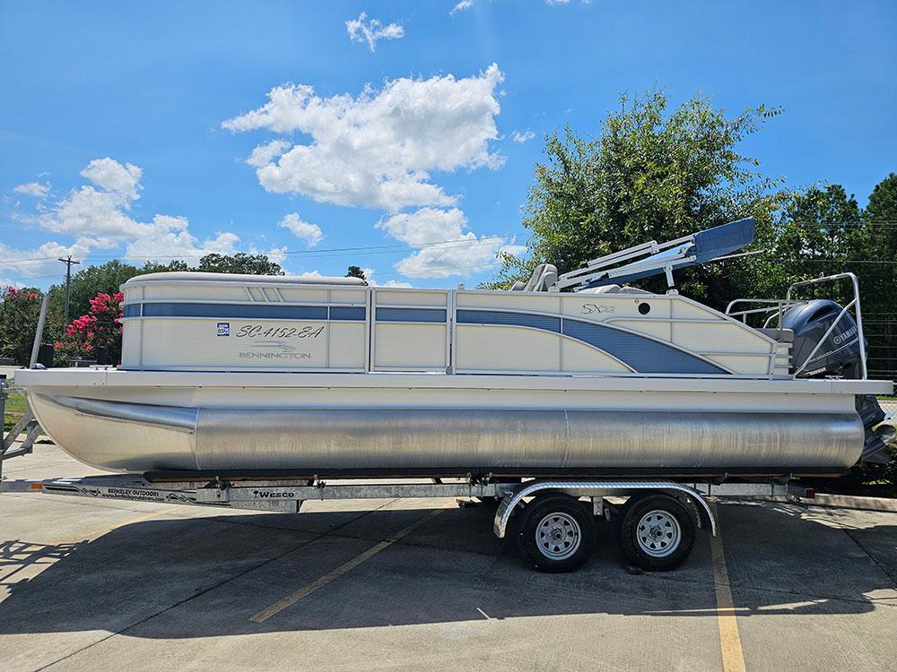 2022 Bennington 22 SXSB pontoon boat on trailer under blue sky.