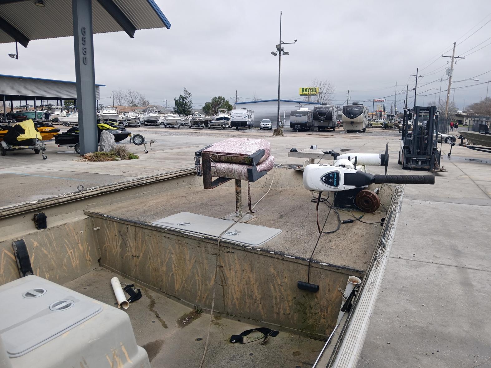 2004 Xpress 18 boat at a marina with equipment and trailers in the background.