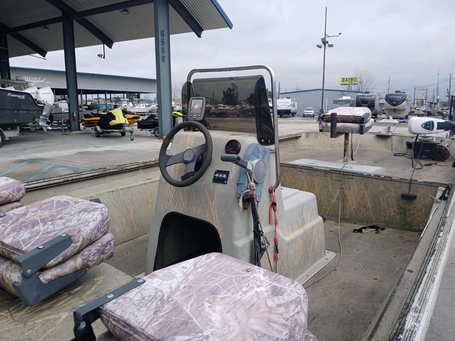 2004 Xpress 18 boat with camouflage seats, steering console, and outdoor showroom setting.