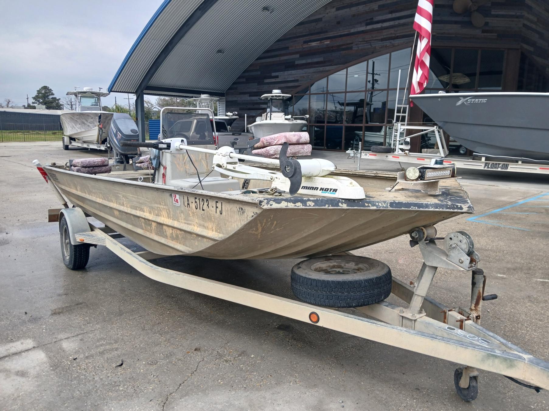 2004 Xpress 18 boat on trailer, parked outdoors near a modern building.