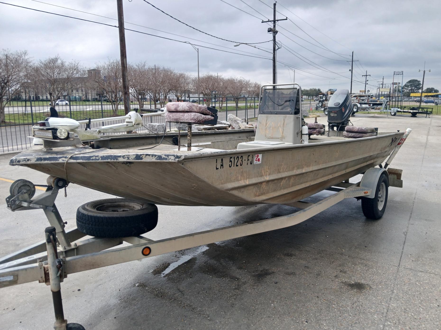 2004 Xpress 18 boat on trailer, parked outdoors on a cloudy day.