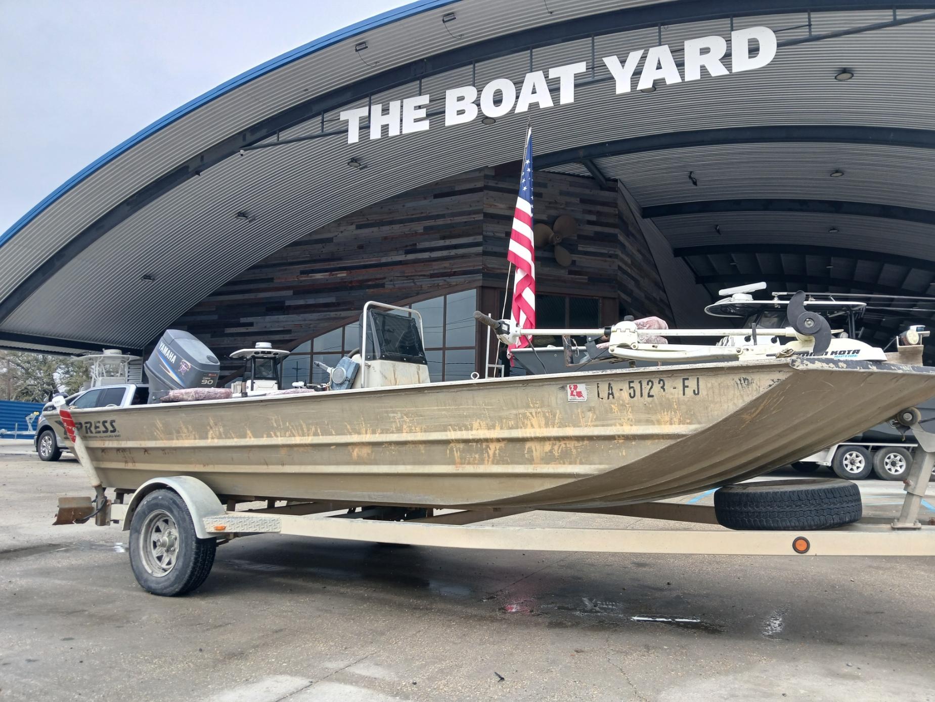 2004 Xpress 18 boat on trailer at The Boat Yard, featuring American flag.