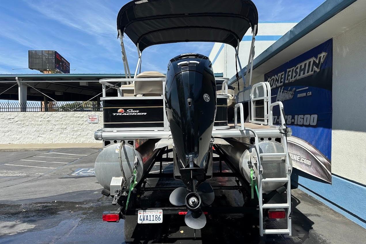 2022 Sun Tracker Bass Buggy 18 DLX pontoon boat with outboard motor, parked outdoors.